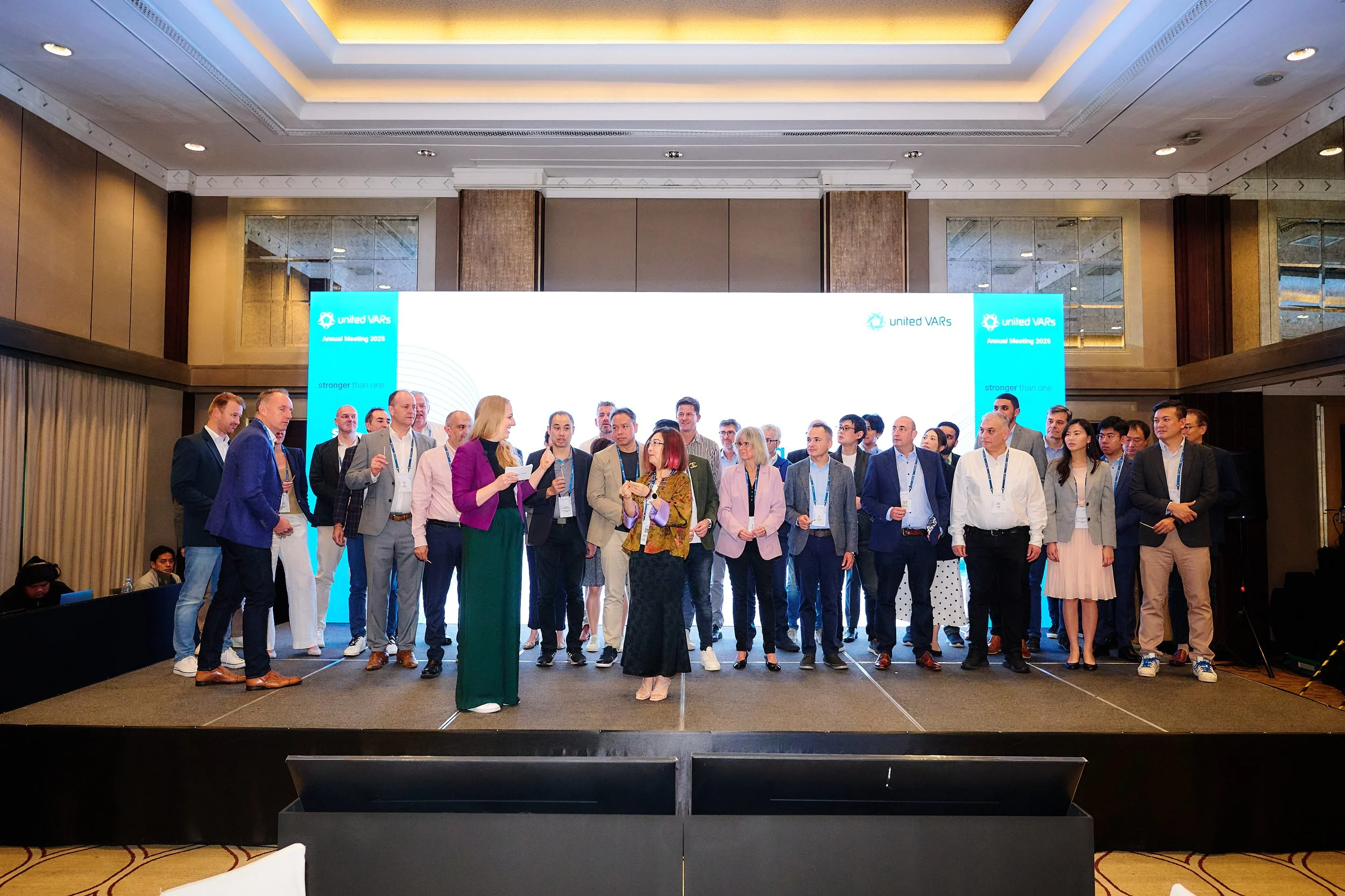 Gruppe von Menschen auf einer Bühne bei einem professionellen Event oder einer Konferenz, mit einem großen Bildschirm im Hintergrund, der 'United VARs' und das Jahr 2023 anzeigt.