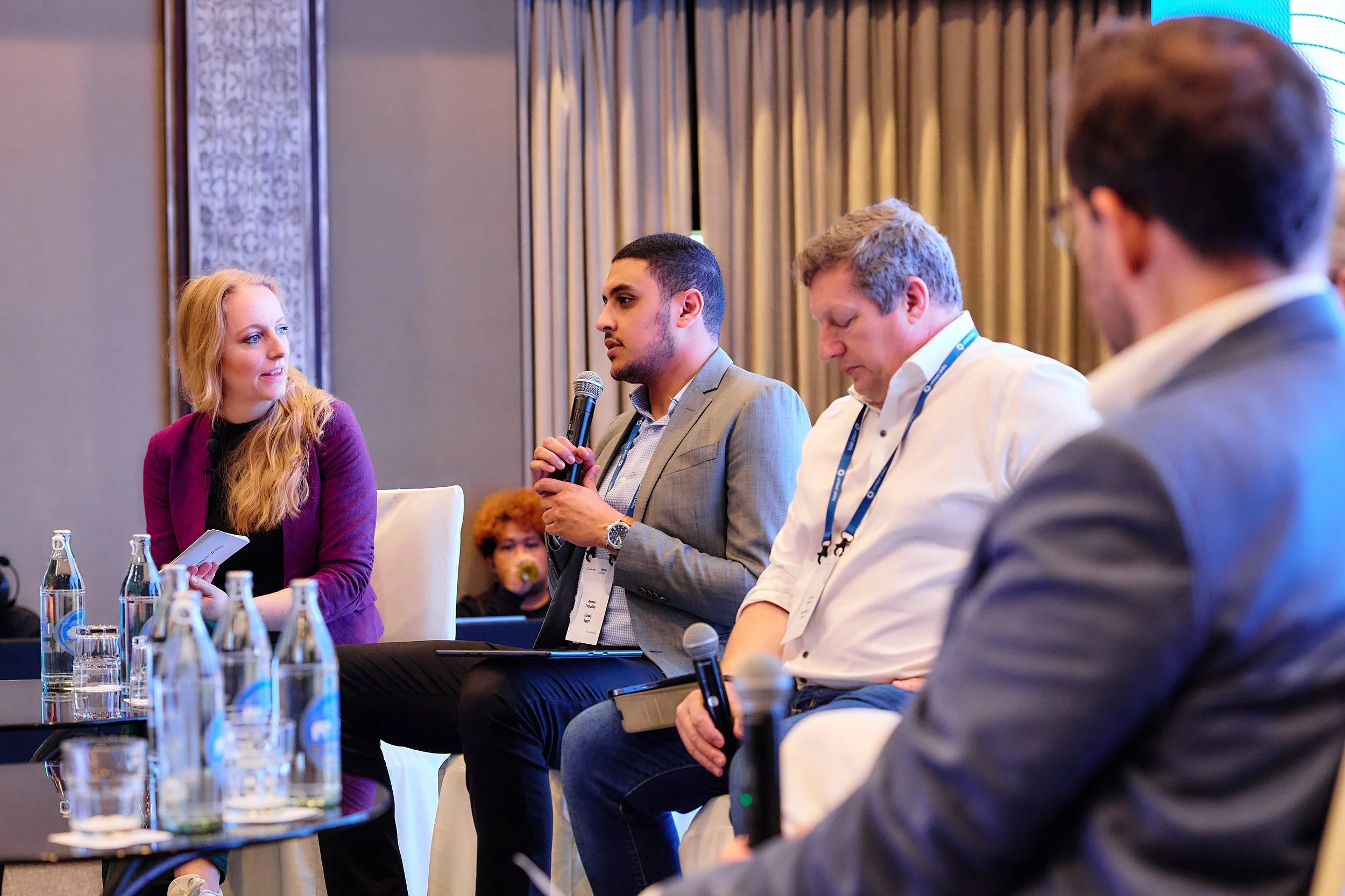 Menschen bei einer Panel-Diskussion auf einer Konferenz, einer spricht mit einem Mikrofon.