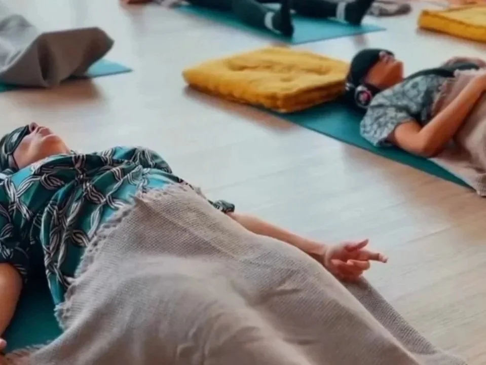 Breathwork, bodywork, somatic unwinding, Kundalini Activation Process. People lying down on yoga mats, possibly participating in a meditation or relaxation session.