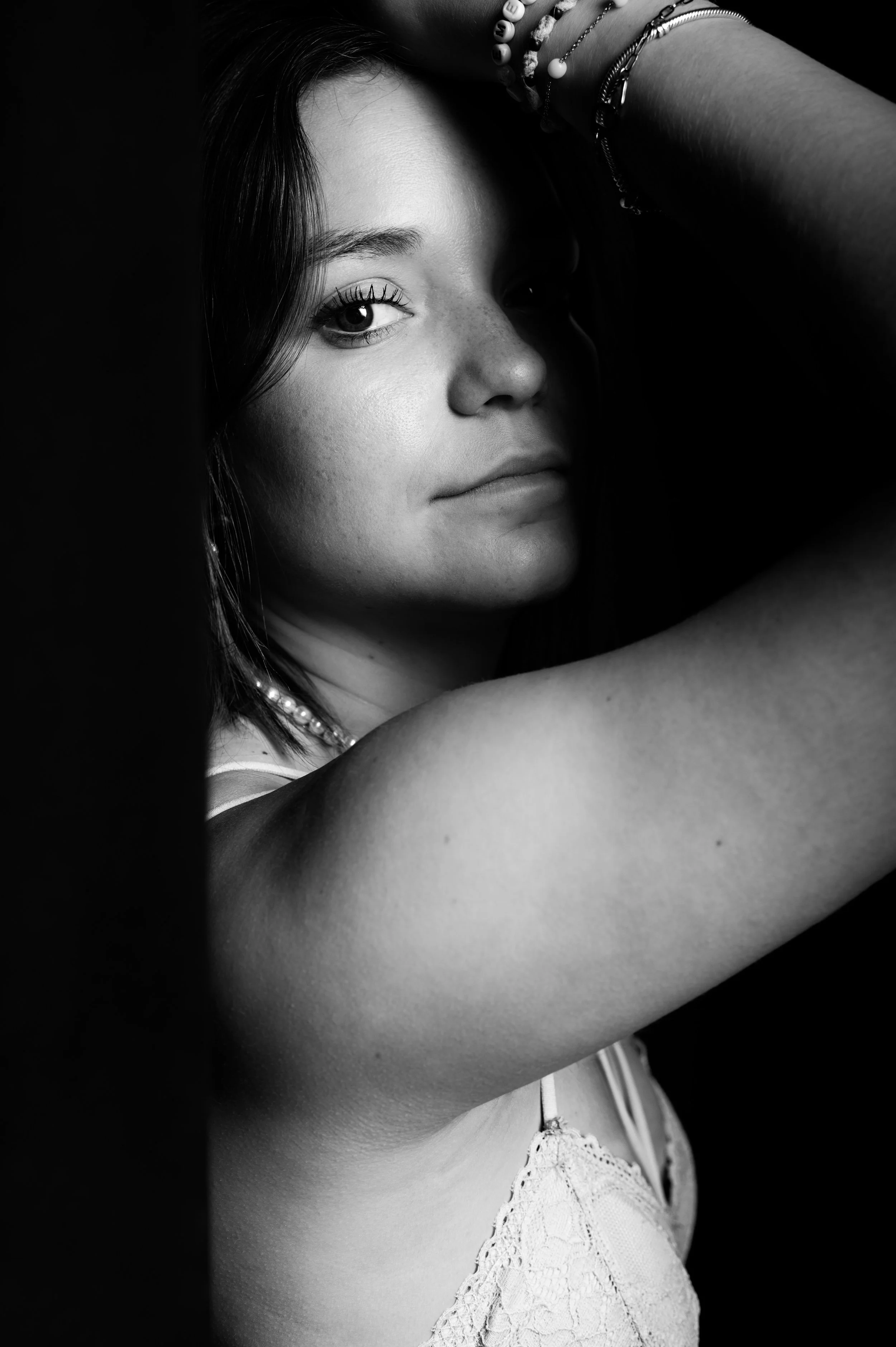 Portrait en noir et blanc d'une femme regardant à la caméra, la tête inclinée, les cheveux courts, portait des bracelets et une robe en dentelle, photographe royan, photographe de femme, portrait de femme, shooting de femme, photo de femme