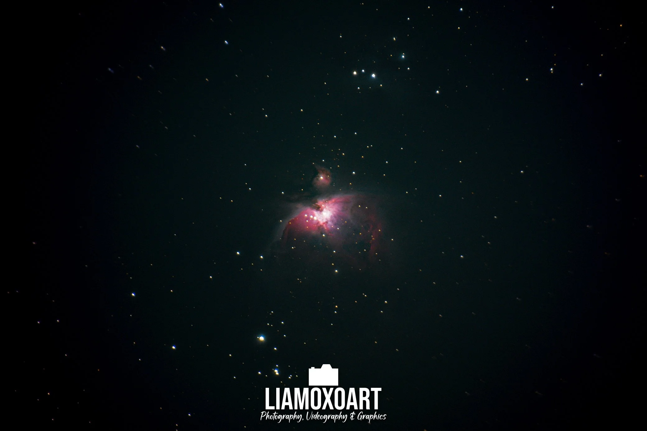 A view of space showing numerous stars and nebula clouds with pink and red hues. There is text at the bottom center of the image that says 'LIAMOXART Photography, Videography & Graphics'.