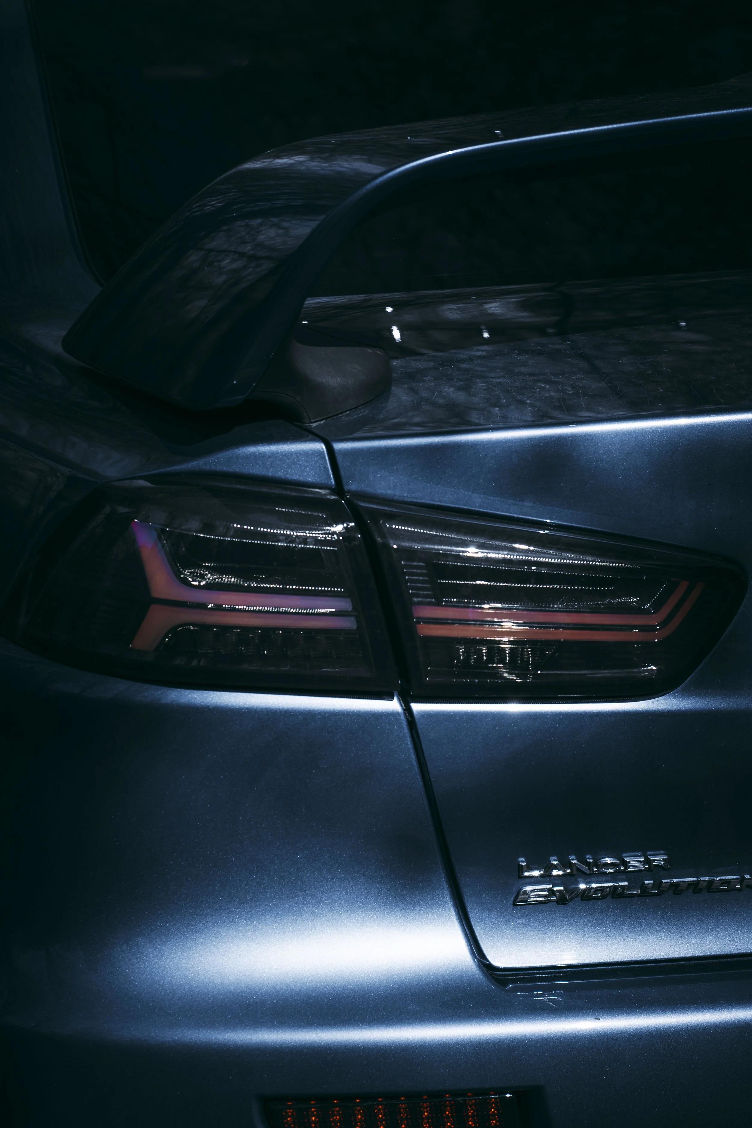 Close-up of the rear of a dark blue Land Rover Evolution vehicle, showing tail light details and part of the trunk.