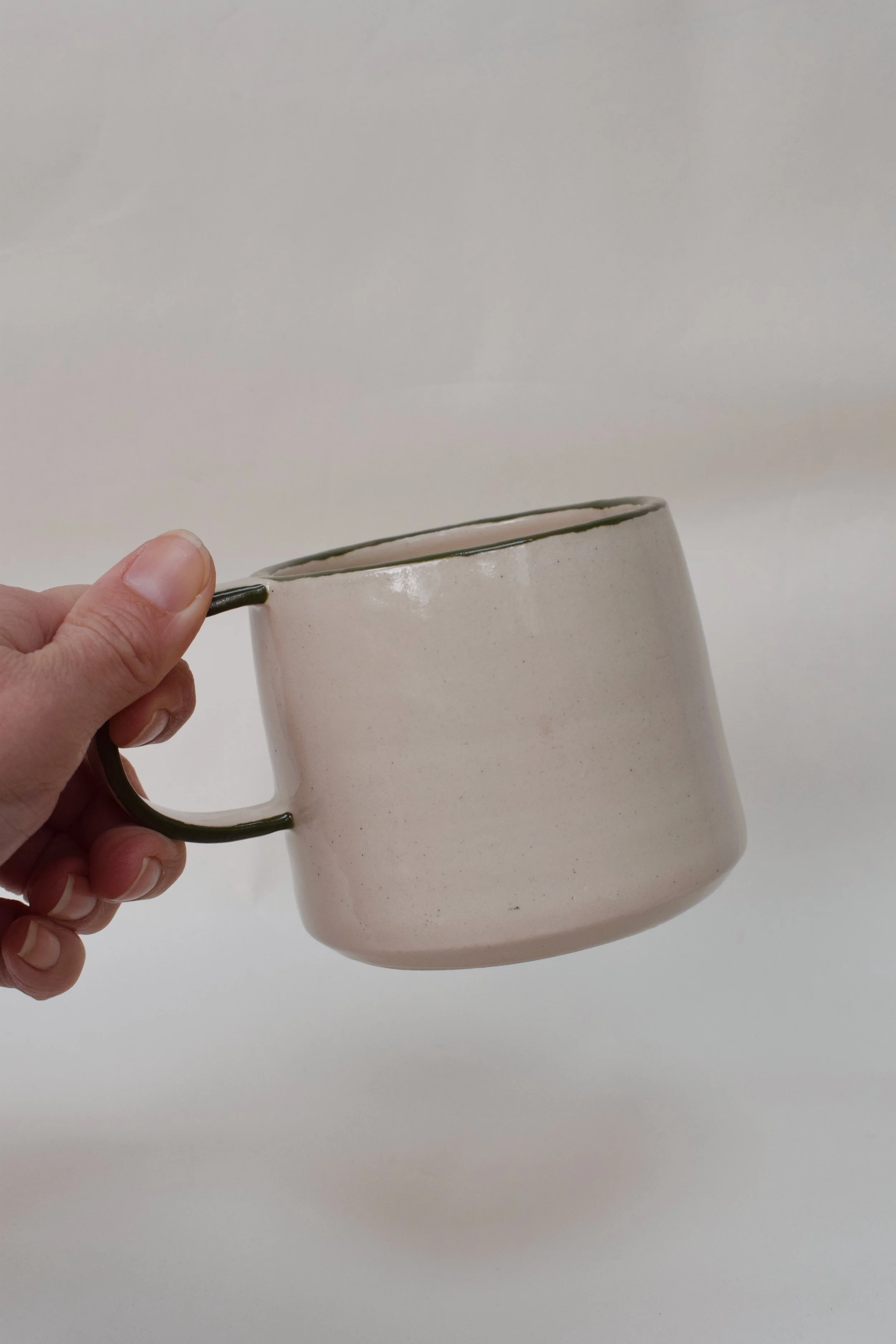 J Lucas Pottery_green edge mug_in hand.jpeg