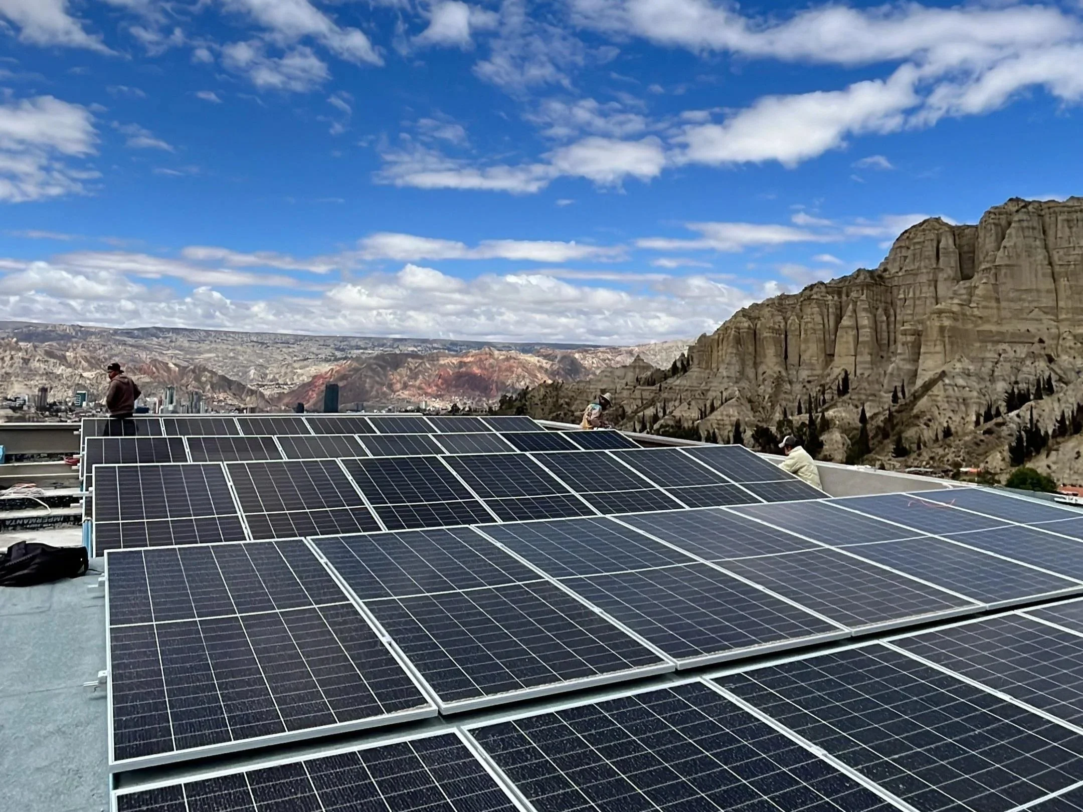 Paneles solares instalados en un edificio con montañas al fondo y cielo azul con nubes. La Paz Bolivia.