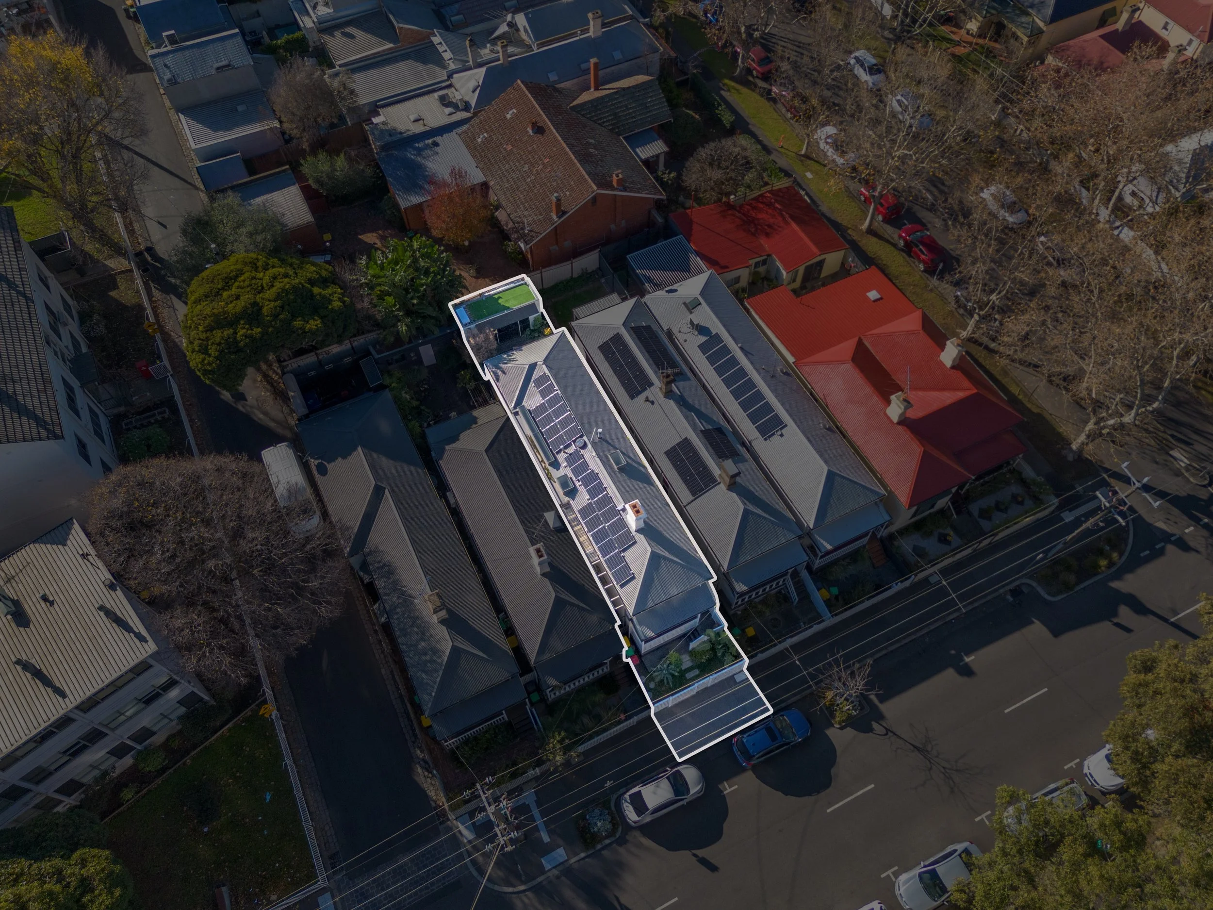 Aerial view of a residential neighborhood with houses, trees, and a few swimming pools, streets, and neighboring buildings along a waterfront.