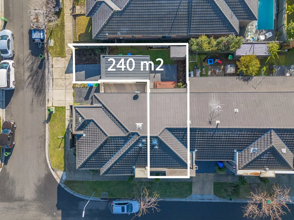 An aerial view of a residential property with a marked area of 240 square meters, showing a backyard, backyard deck, neighboring houses, and parked cars along the street.