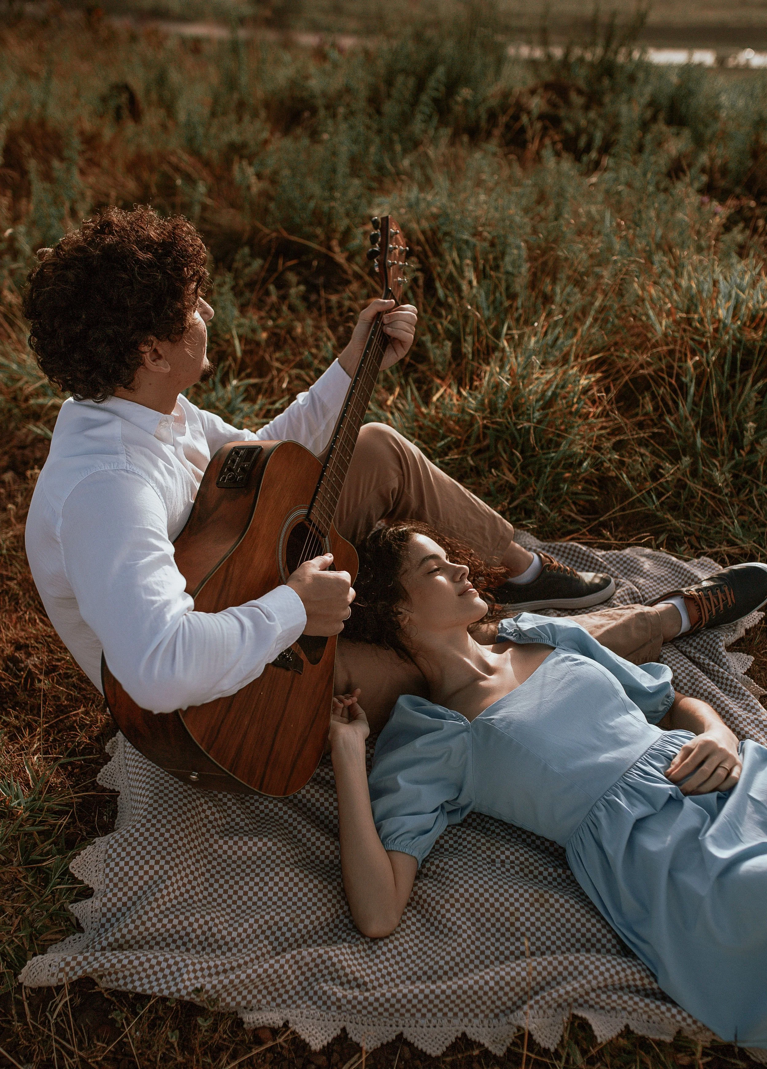 person laying on their partner's lap while they are playing guitar