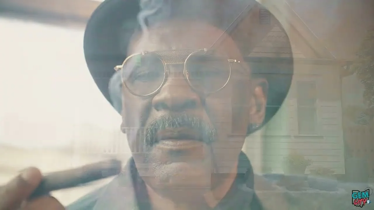 A man wearing sunglasses, a wide-brimmed hat, and smoking a cigar, with reflections of buildings on the glass surface.