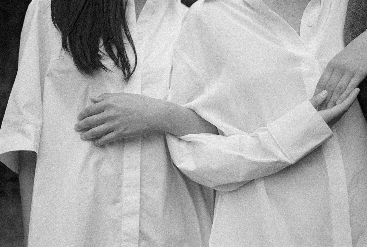 Zwei Frauen in weißen Hemden, eine hält den Arm der anderen, Schwarz-Weiß – Sinnbild für die kleine Gruppe und den Zusammenhalt im Self-Leadership Lab.