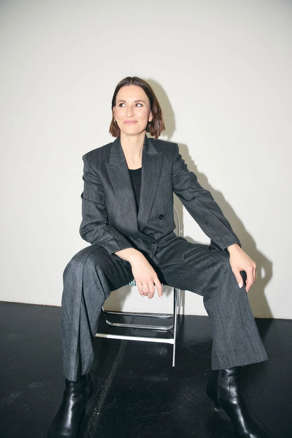 Valerie Junger im grauen Anzug sitzt selbstbewusst und blickt zur Seite – Coaching für berufliche Klarheit und Neuorientierung.