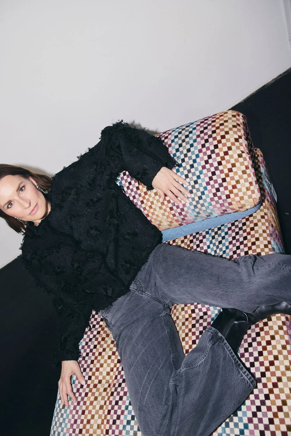 Valerie Junger, systemische Coachin und Mentorin, sitzt entspannt auf einem bunten Karo-Sofa und blickt in die Kamera.