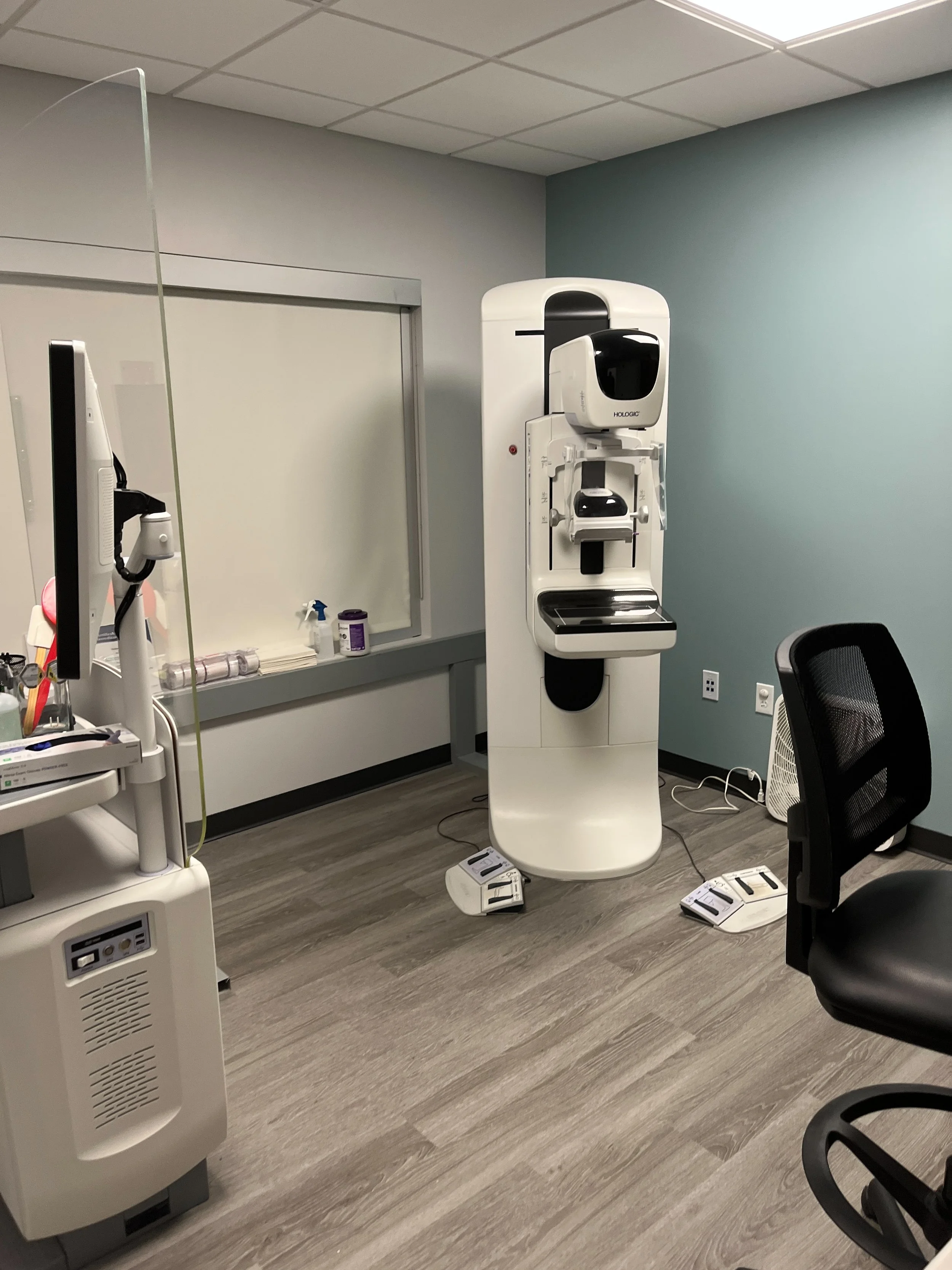 A medical room with an MRI machine, a chair, and medical equipment.