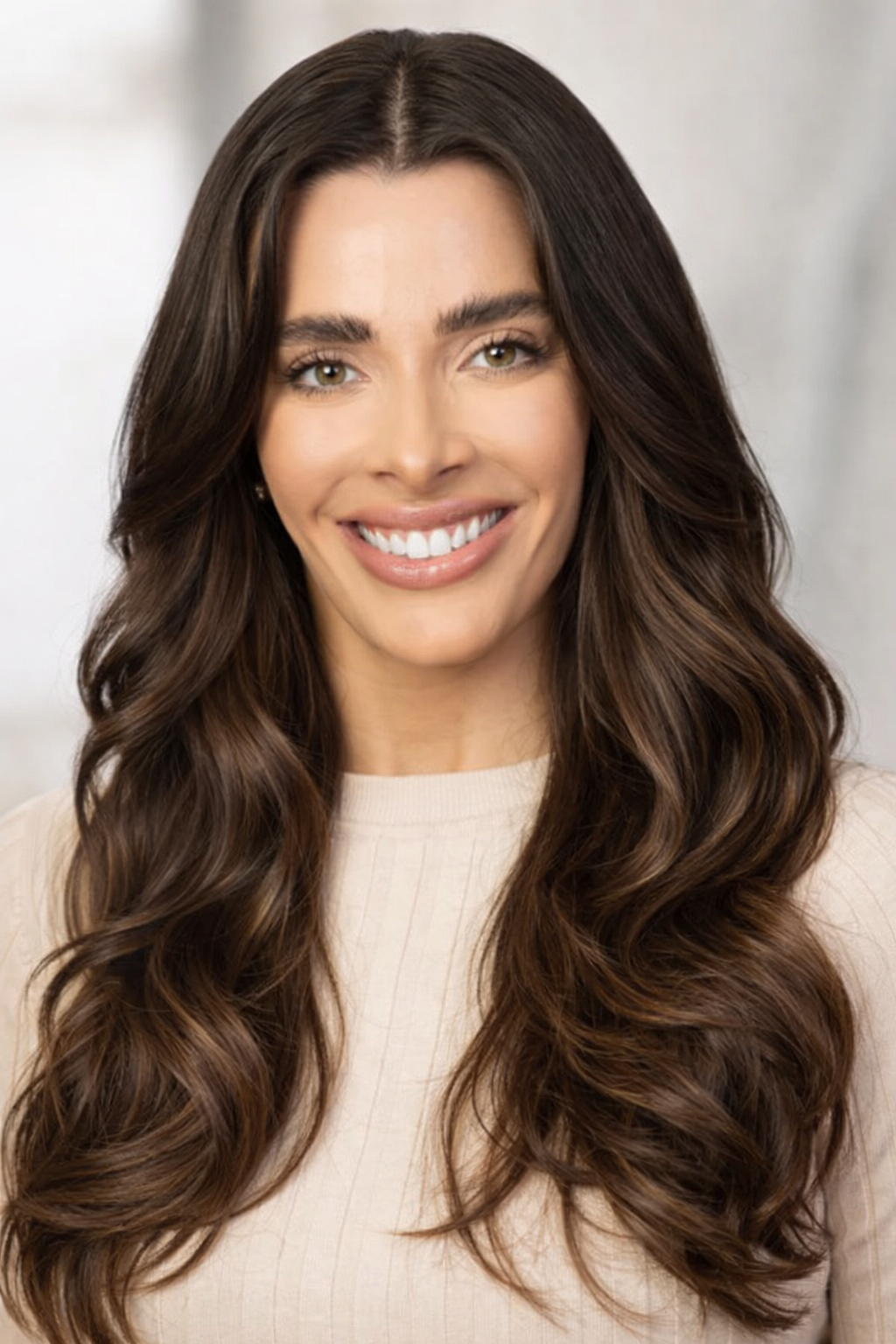 A woman with long dark hair, smiling, wearing a light-colored top, in a professional setting.  Located in Chicago IL.