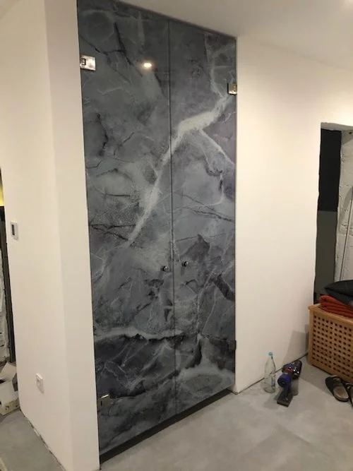 Schrank mit schwarzem Marmor-Design in einem Raum, neben einem schwarzen Körbe und Werkzeugen.