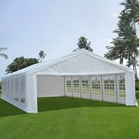 Large white event tent set up on a grassy field with palm trees in the background.