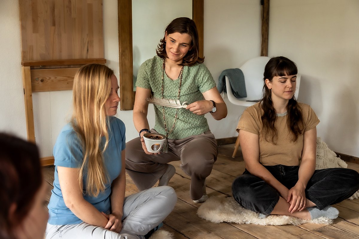 Frauen sitzen in einem Kreis in einem achtsamen Workshop und nehmen gemeinsam Düfte und Räucherwerk bewusst wahr.