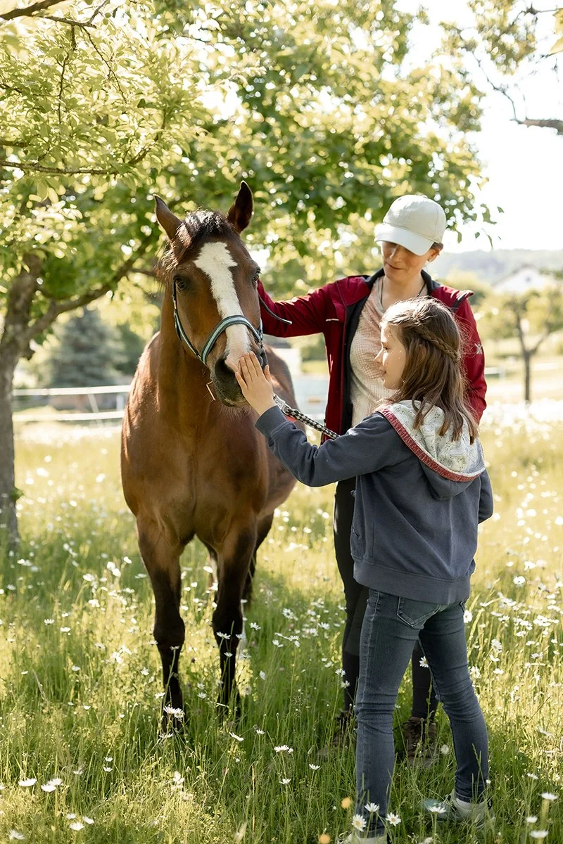 Kind und Pony verbringen einen ruhigen Moment in der Natur und erleben Nähe, Vertrauen und Verbundenheit.