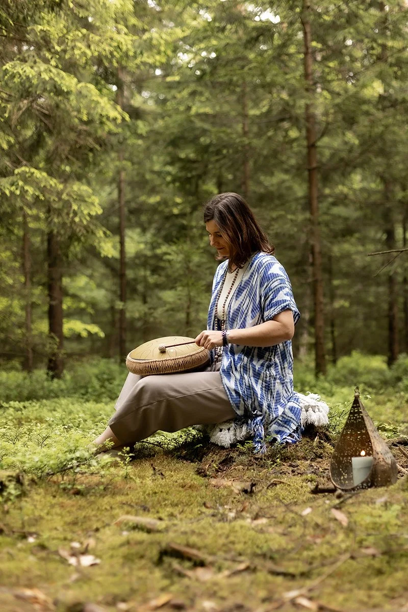 Entspannungs-Retreat im Nürnberger Land: Eine Frau spielt eine Sonic Energy Drum in einem kraftvollen Waldambiente und genießt die Ruhe und Verbundenheit mit der Natur.