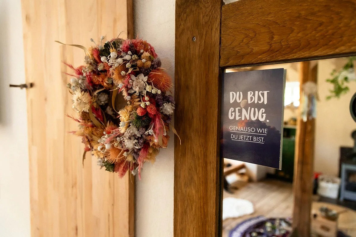 Ein decorativer Trockenkranz aus getrockneten Blumen und Gräsern an einer Tür im Wohndekor. Du bist genug so wie du bist. Ändere deine Glaubenssätze.