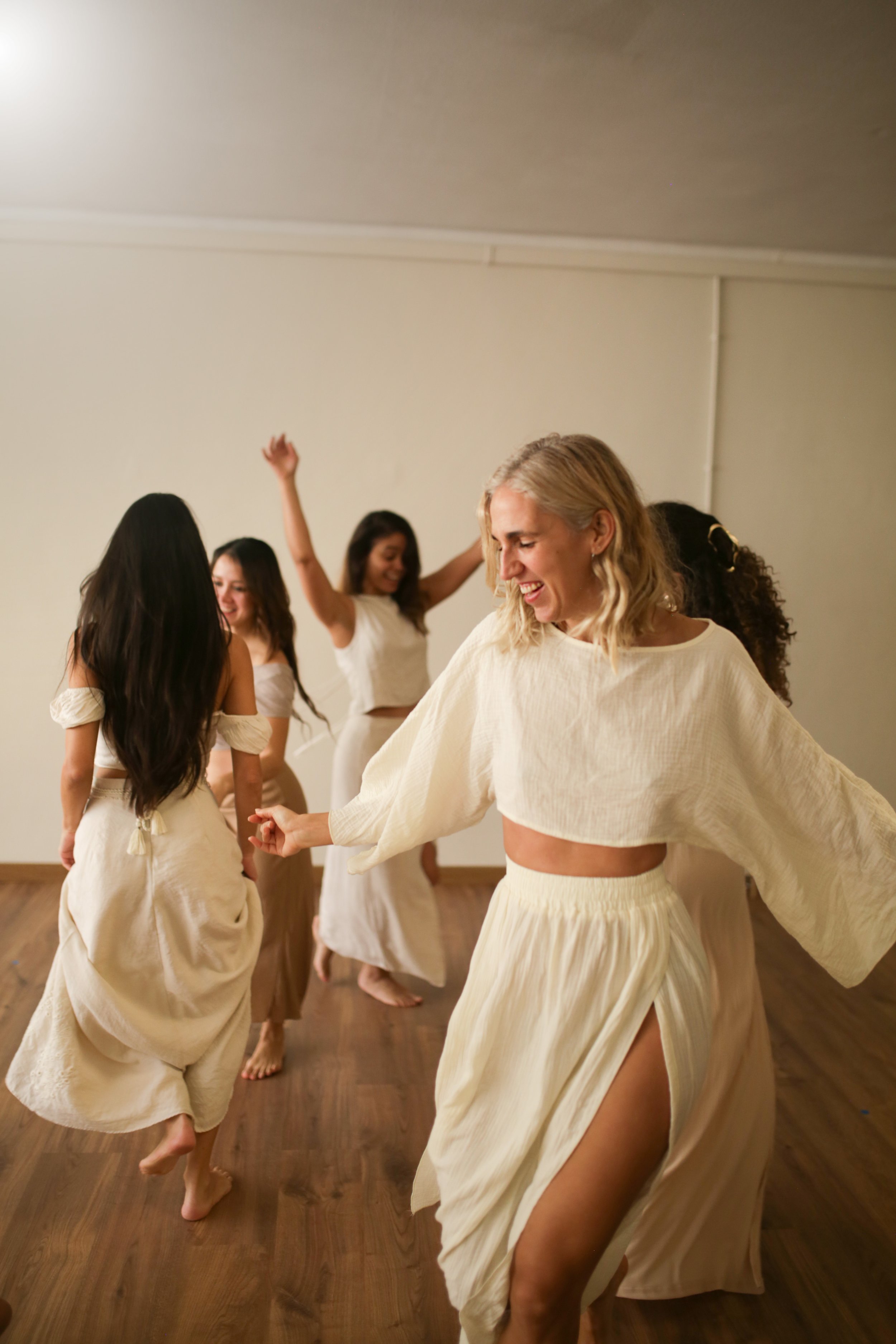 Un grupo de mujeres disfrutando y riendo mientras bailan en un taller de mujeres.