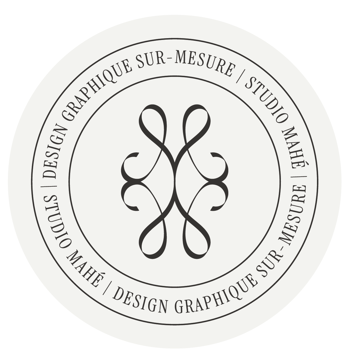 Logo circulaire monochrome avec le symbole du Studio Mahé, entourée par le texte en français et anglais: "Design Graphique Sur-Mesure" et "Custom Graphic Design".