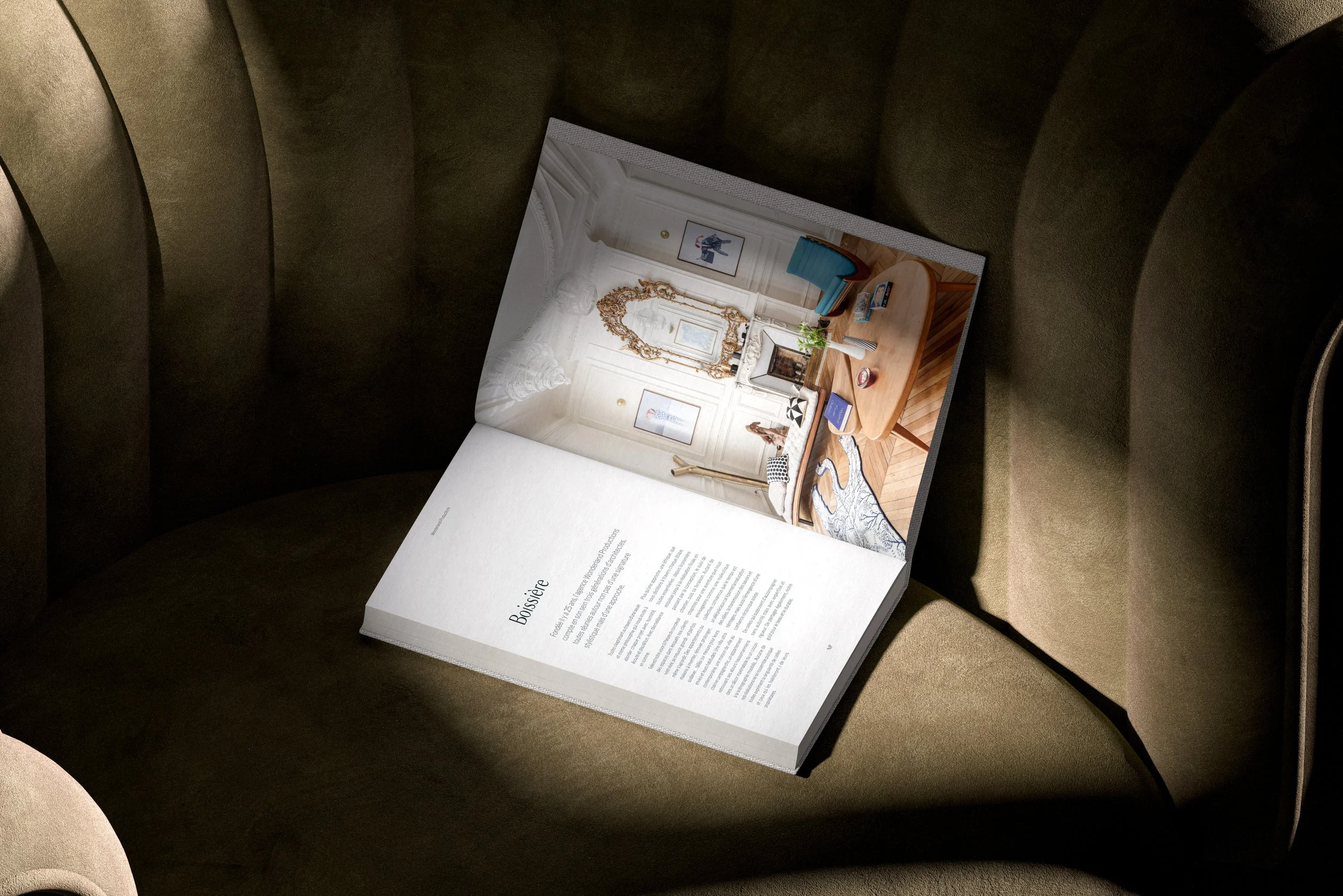 Book de Wonderland Productions (cabinet d’architecture) ouvert sur une double page  présentant un projet d’architecture, posé sur un fauteuil en tissu.