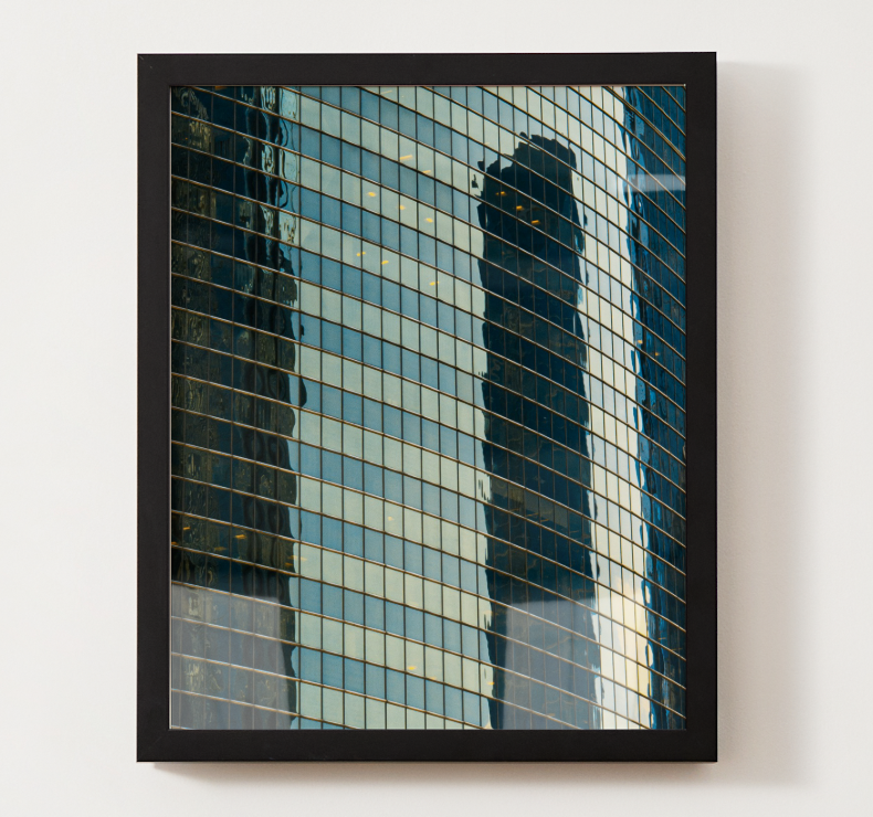 Reflection of modern glass skyscrapers in a framed window.