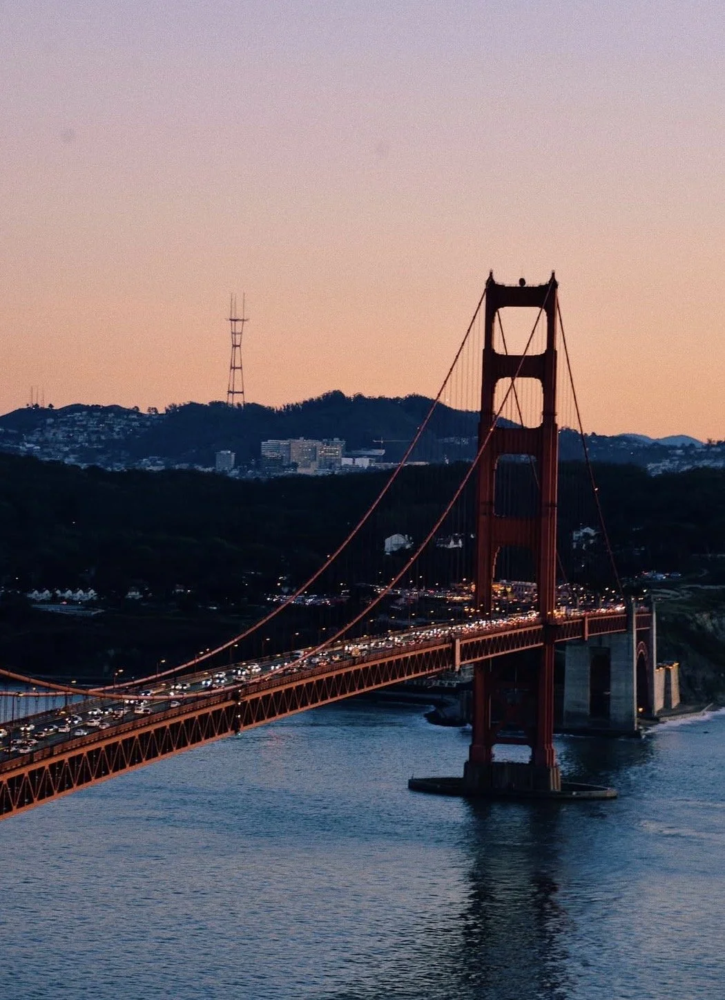 The Golden Gate Bridge in San Francisco at sunset with cars on the bridge and hills in the background.
