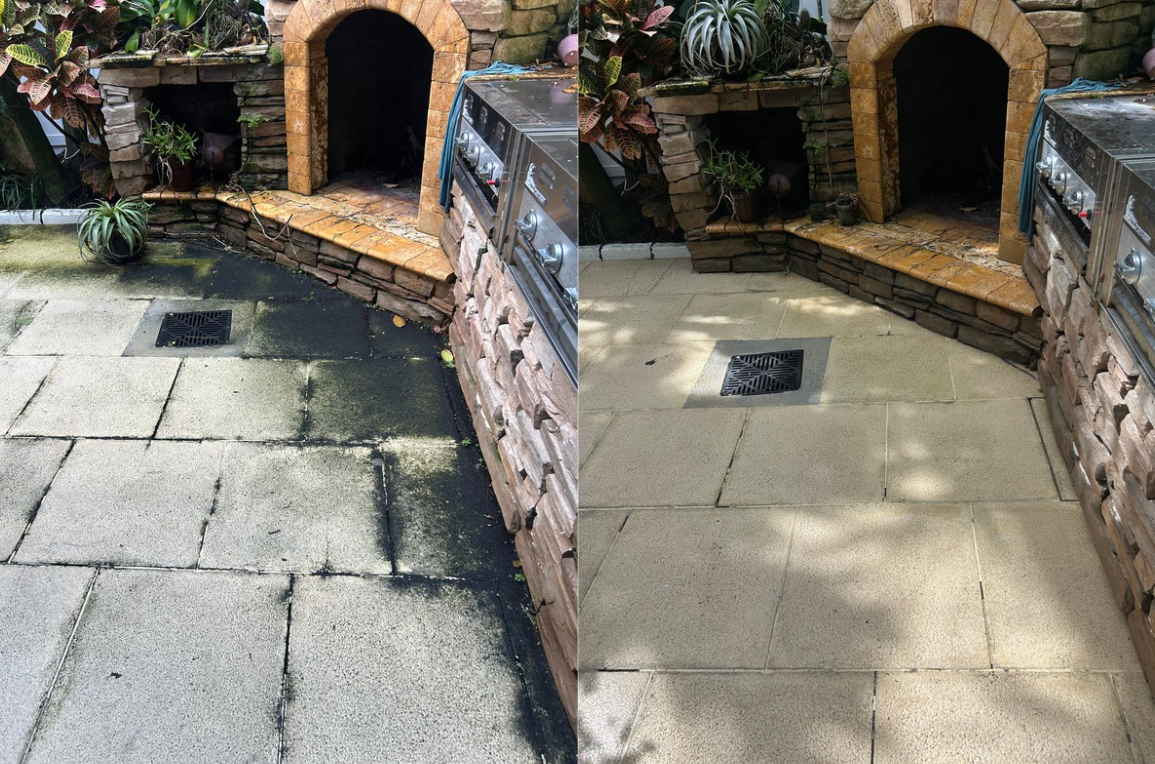 Comparison of outdoor patio flooring before and after cleaning or renovation, showing a dirty, black, stained concrete surface on the left and a clean, light-colored, finished surface on the right, with a brick fireplace in the background.
