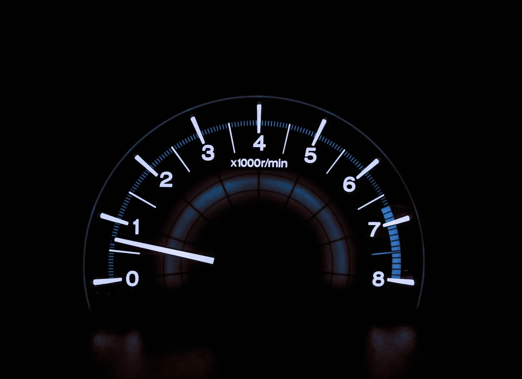 Car tachometer showing approximately 1,000 RPM in a dark environment.