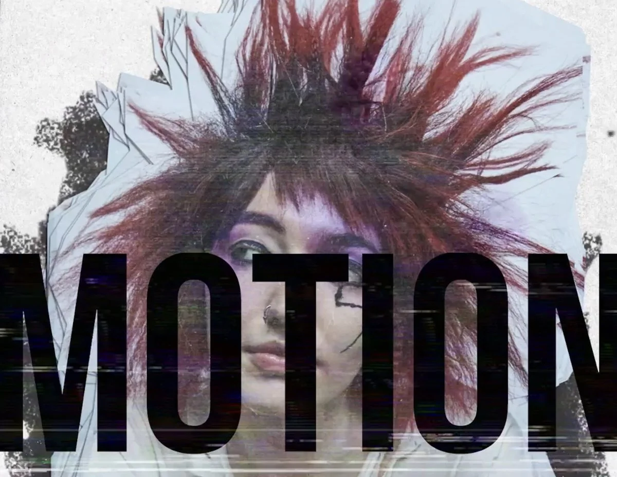 Person with vibrant, spiky red hair and heavy makeup lying on a bed with large black text reading "MOTION" across the image.