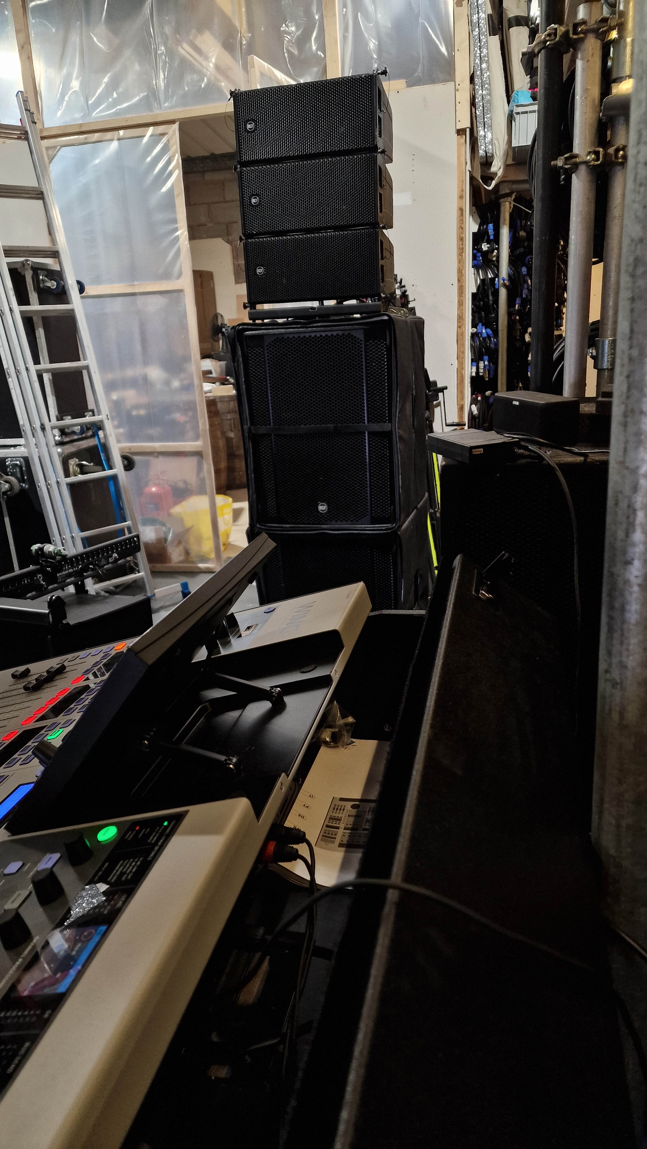 Sound equipment setup including stacked speakers, audio mixer, and other tech gear in a backstage or production area.