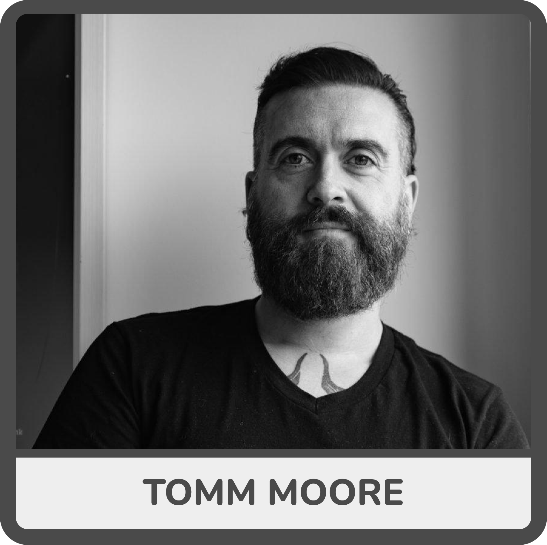 Black and white portrait of a man with a beard and short hair, wearing a black shirt, with the name 'Tomm Moore' below the image.