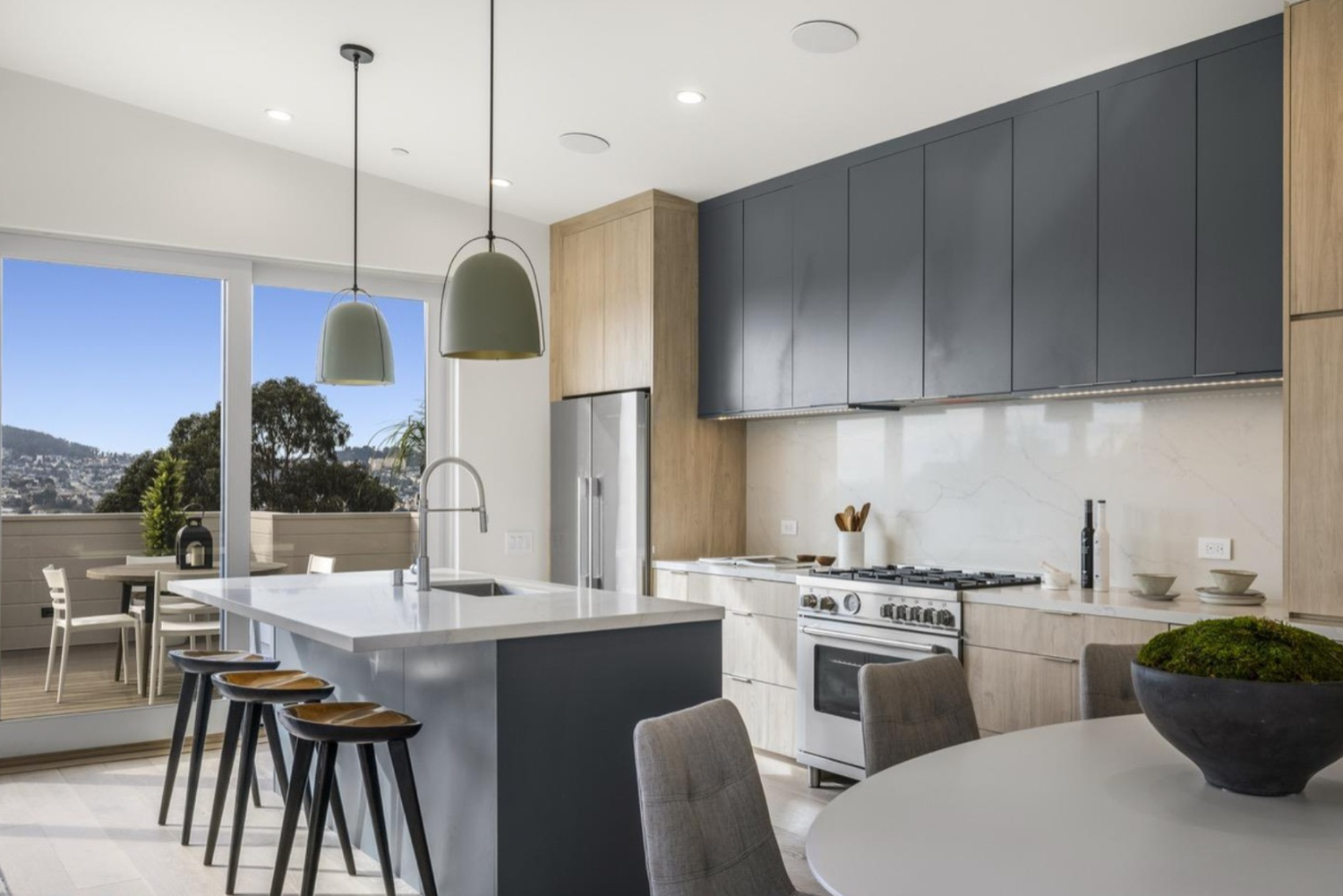 Modern kitchen with white cabinetry, a farmhouse sink, stainless steel dishwasher, potted plants, and wooden flooring.
