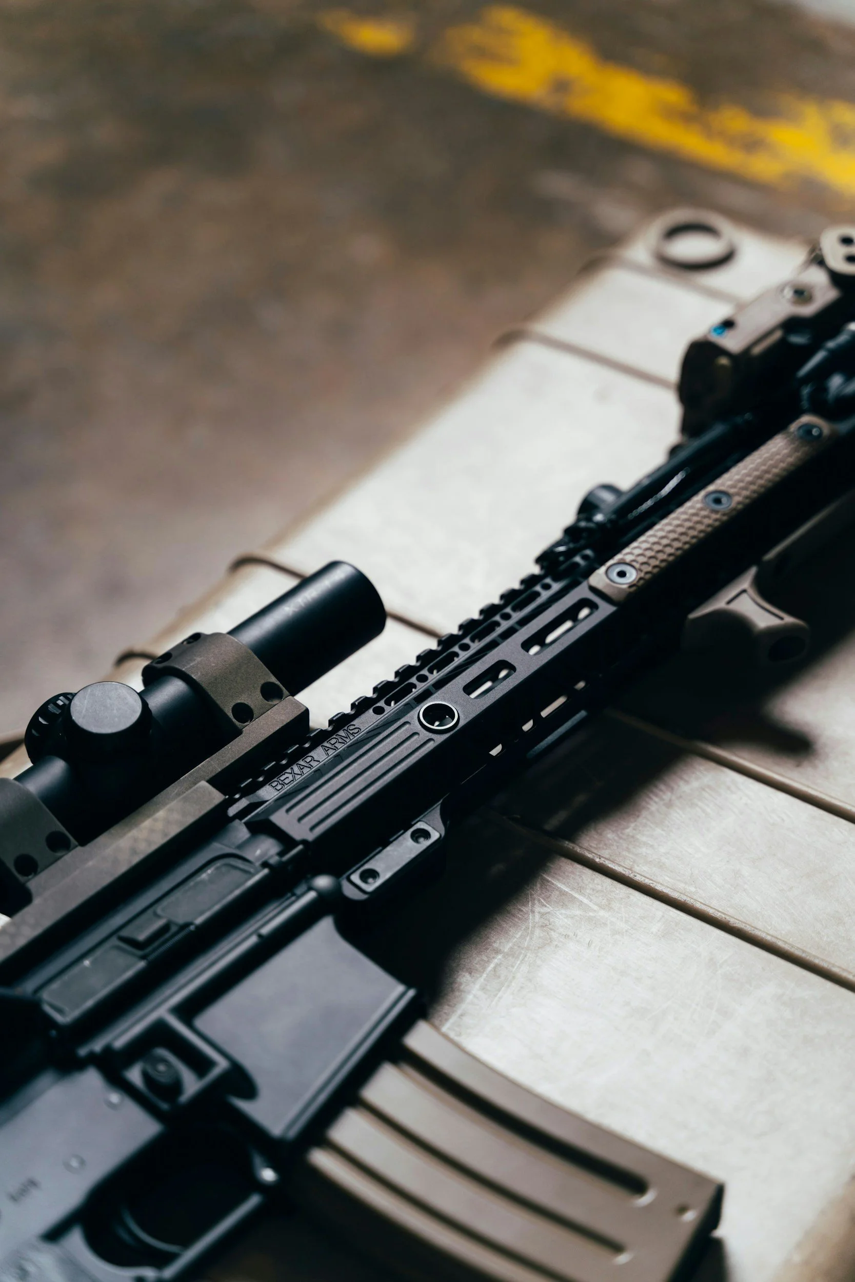 Close-up of a black firearm with a mounted scope emphasizing firearm machining experience.
