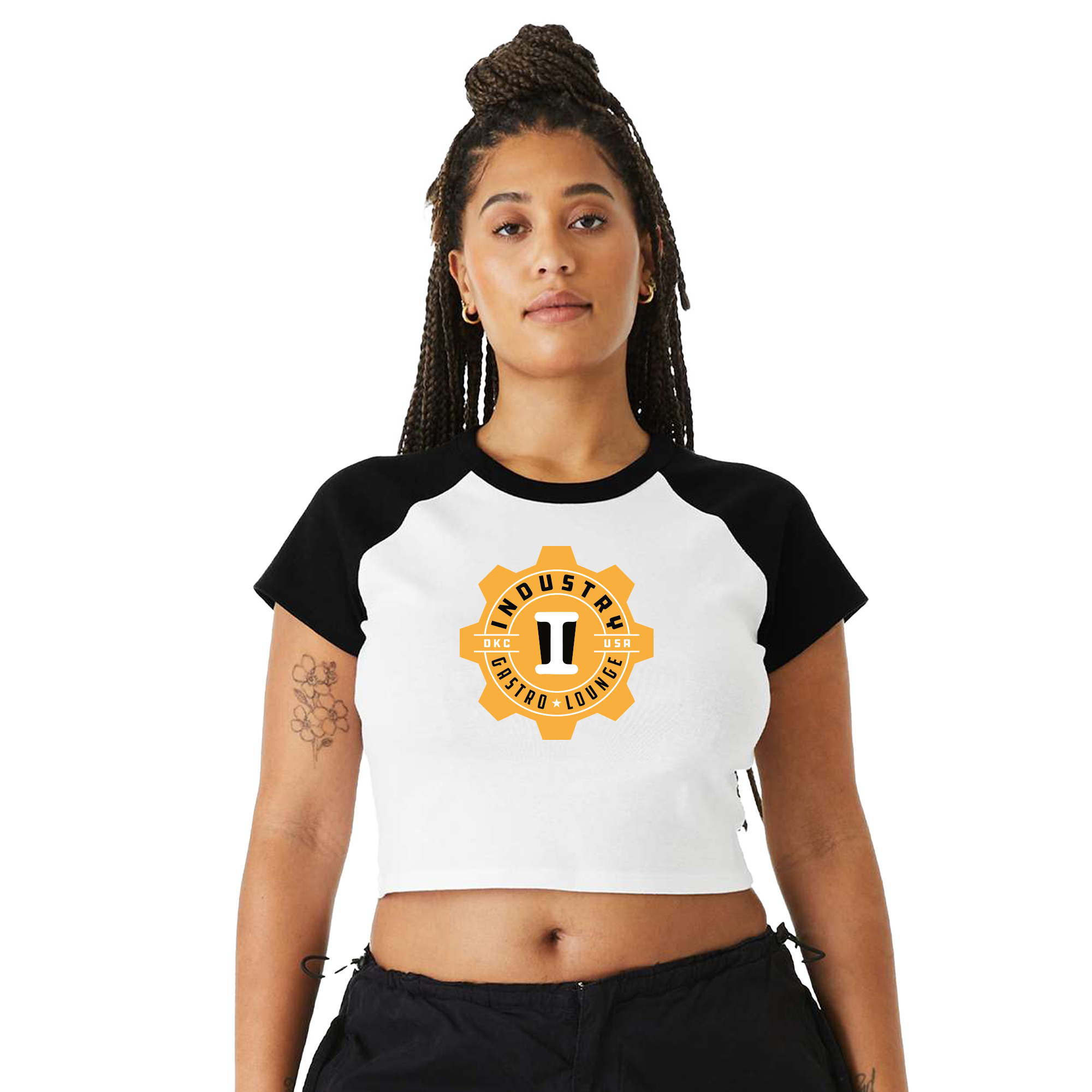 A young woman with dreadlocks, wearing a white and black cropped T-shirt with a logo that says 'Industry Café Lounge' and 'OKC USA' on it.