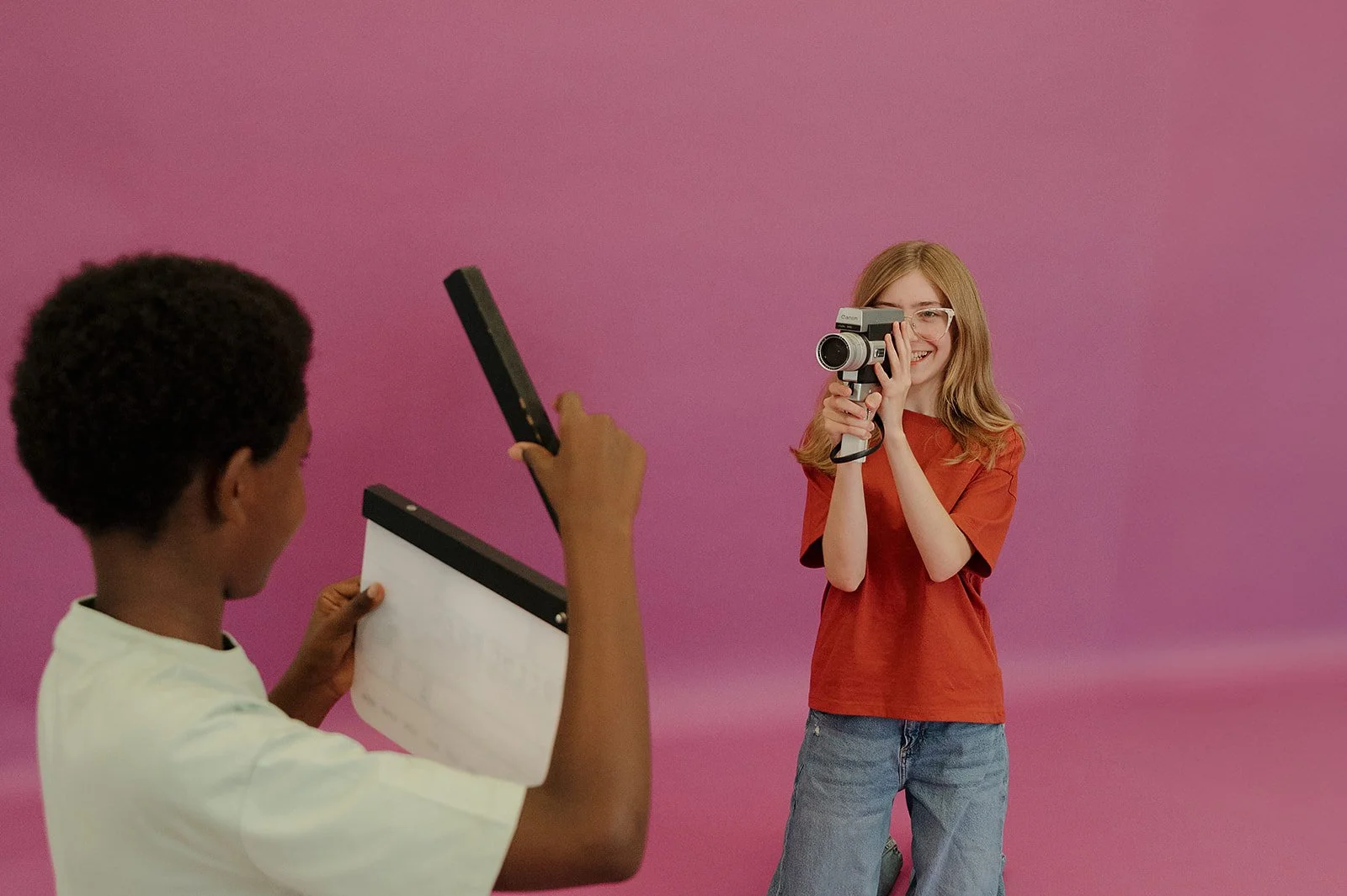 A girl shooting a video of a boy with a film clapper