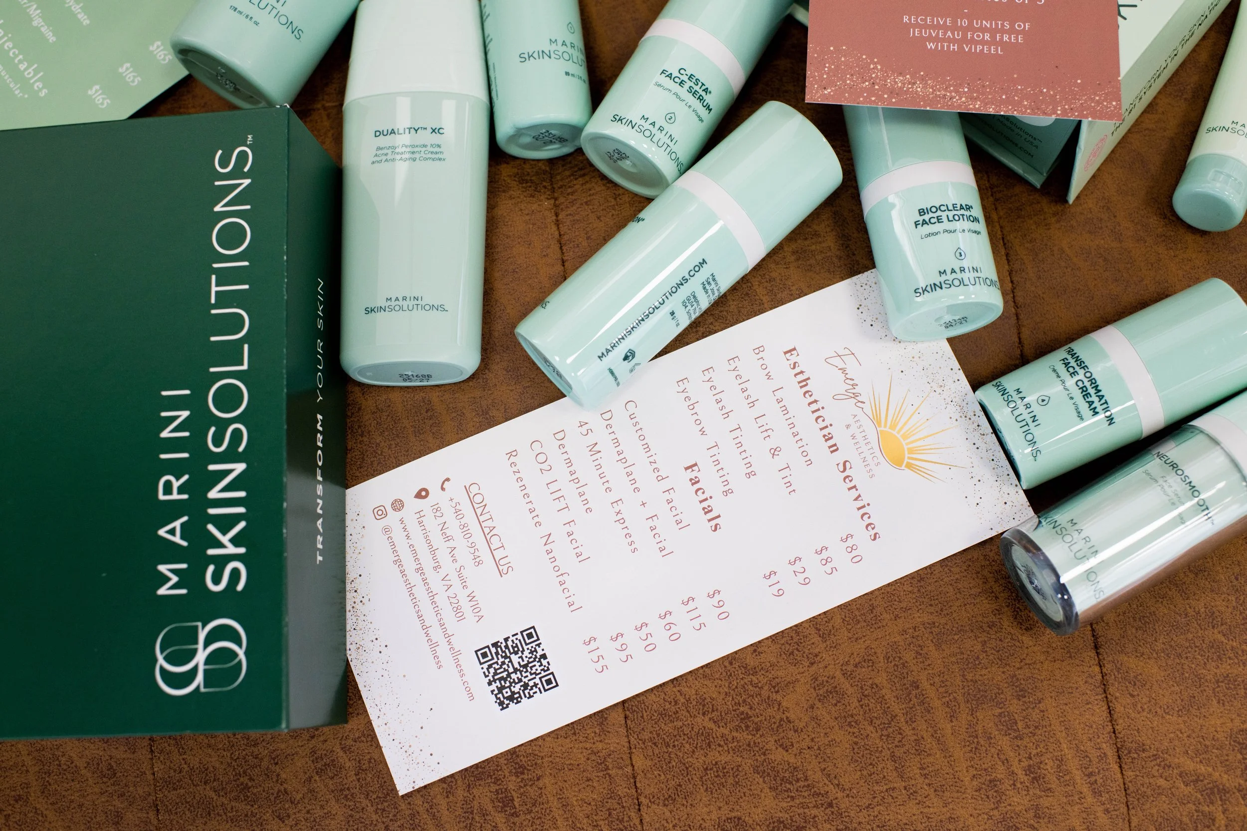 Collection of skincare products and a services menu from Marini Skin Solutions on a wooden table.
