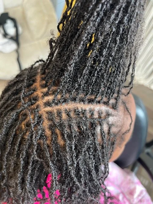 The image shows a person with freshly styled locs, with the scalp visible in a parting section, and the locs are textured and twisted.