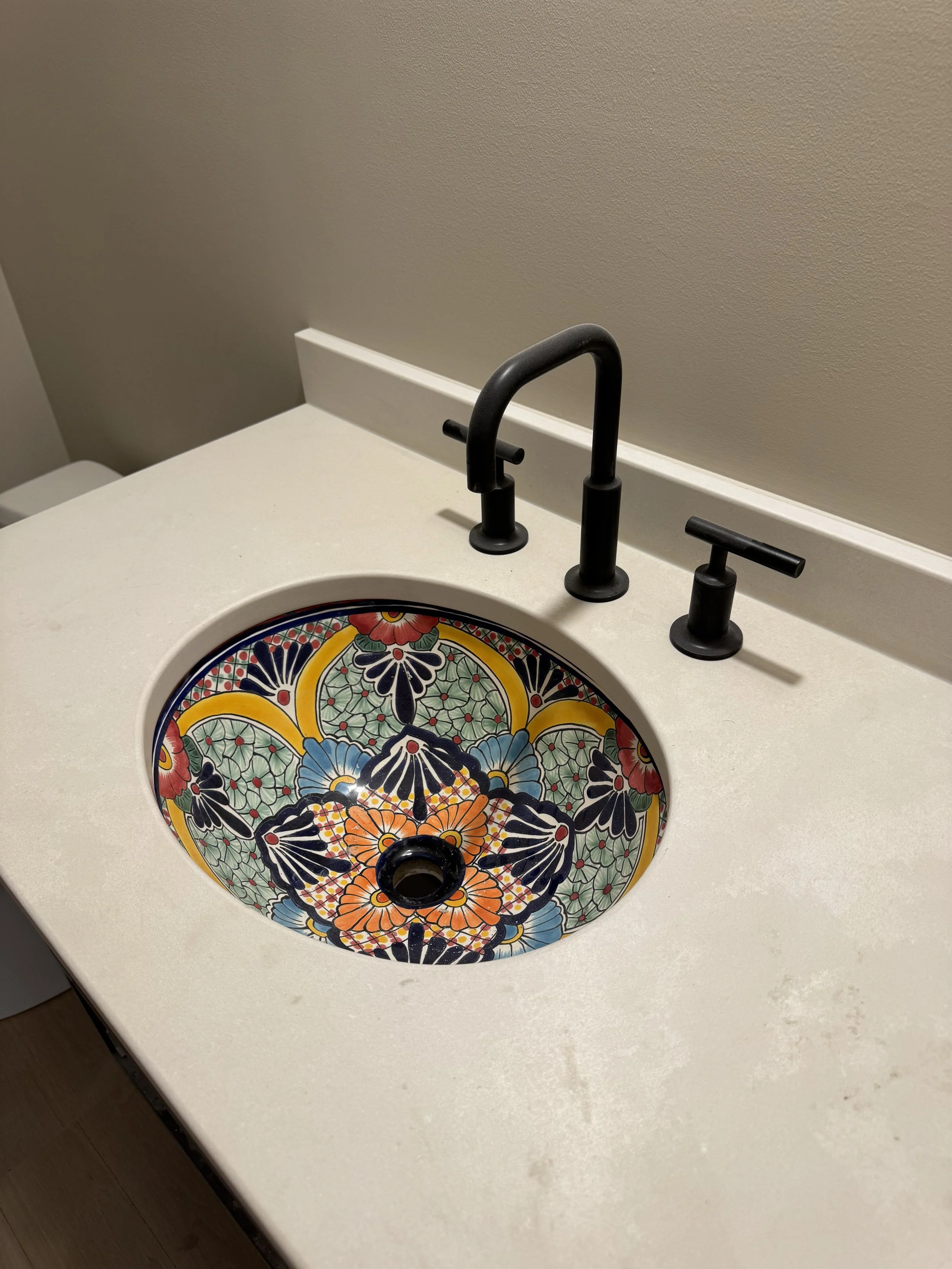 Bathroom countertop with a colorful, patterned sink and black faucet.