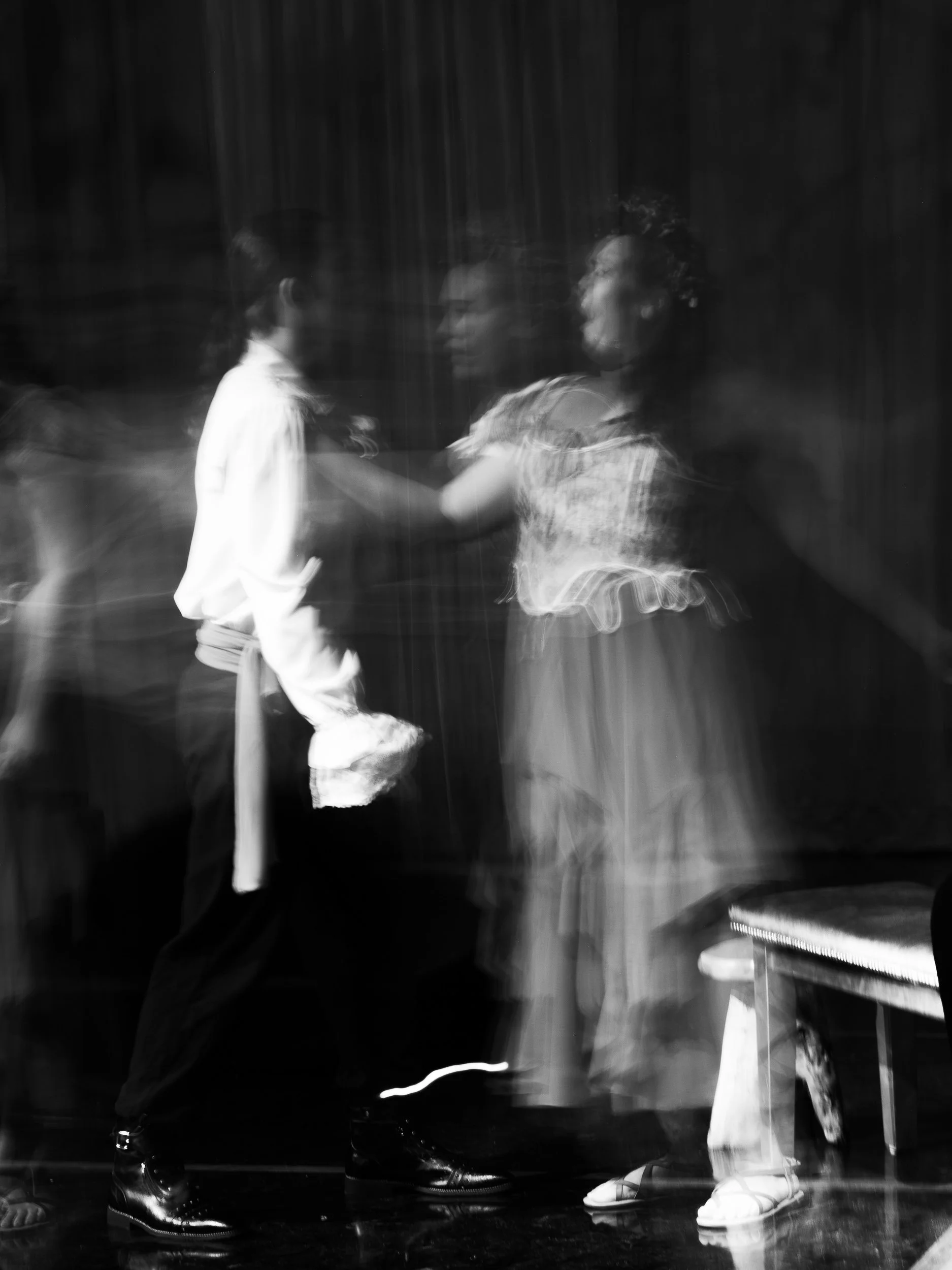Two women dancing on stage, blurred motion in black and white.