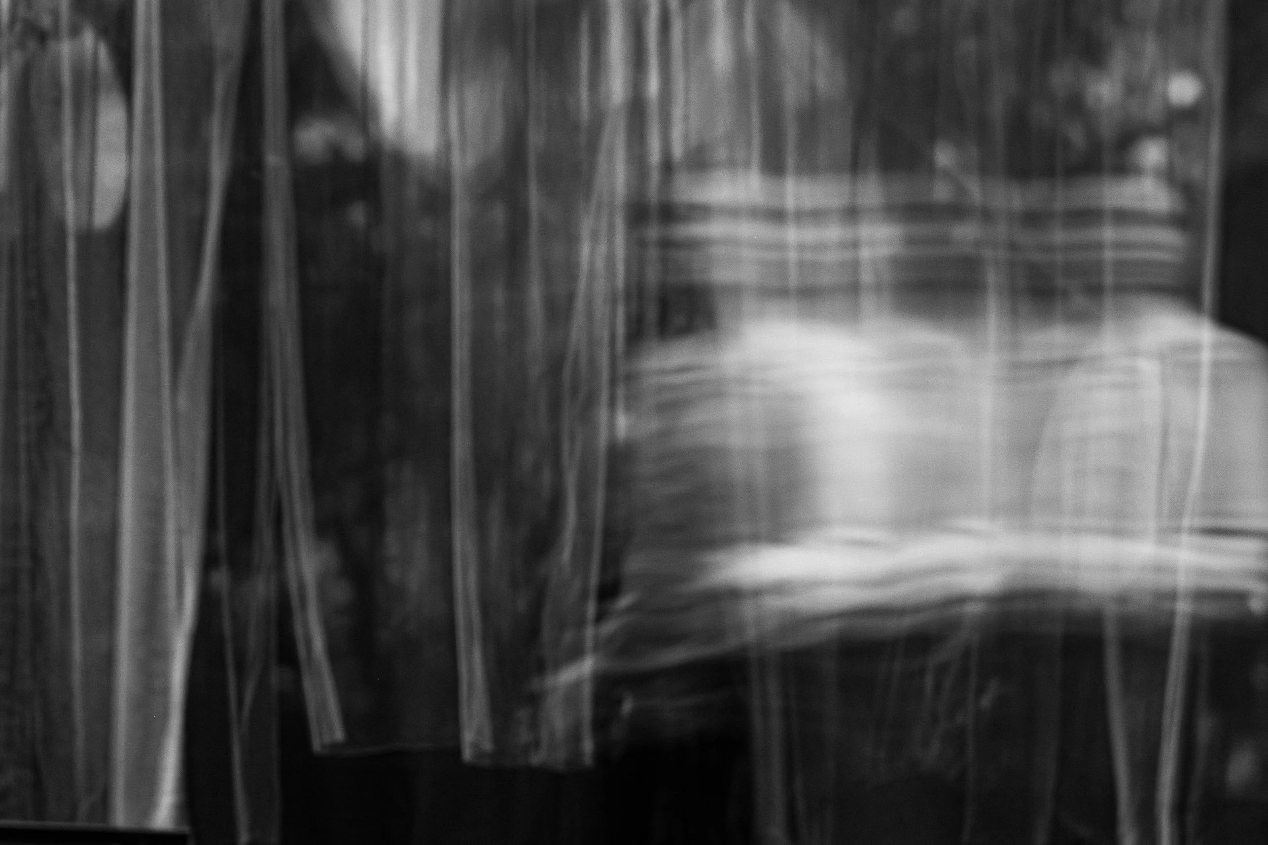 Clothes hanging behind a transparent plastic curtain.