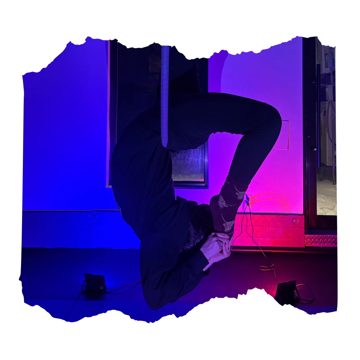 Person in a yoga pose in front of colorful purple and blue background with cables on the floor.