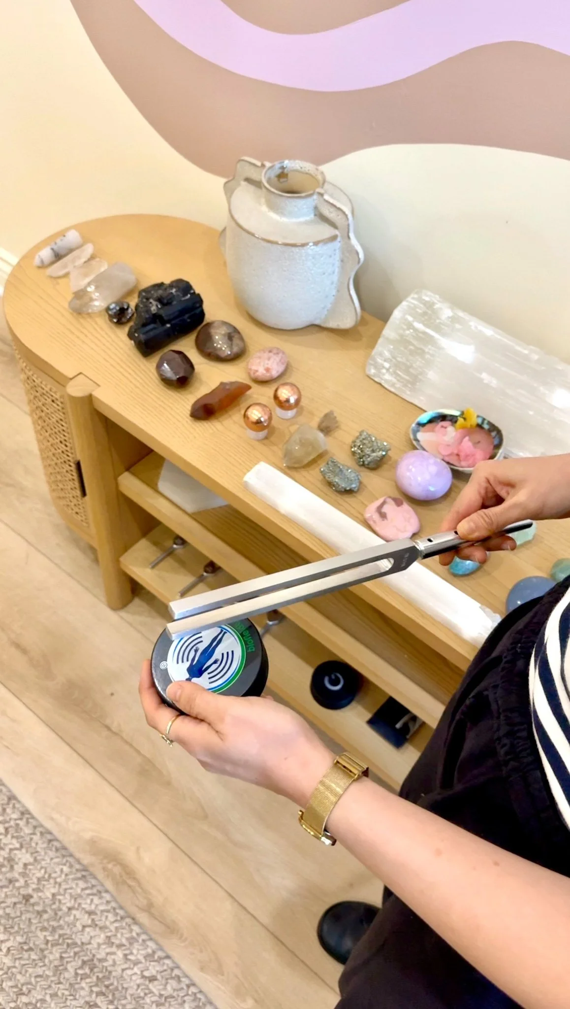 Tomoko holding a 174 hz unweighted tuning fork with a Biofield Tuning hocky puck at Open Eye Crystals Healer's Room