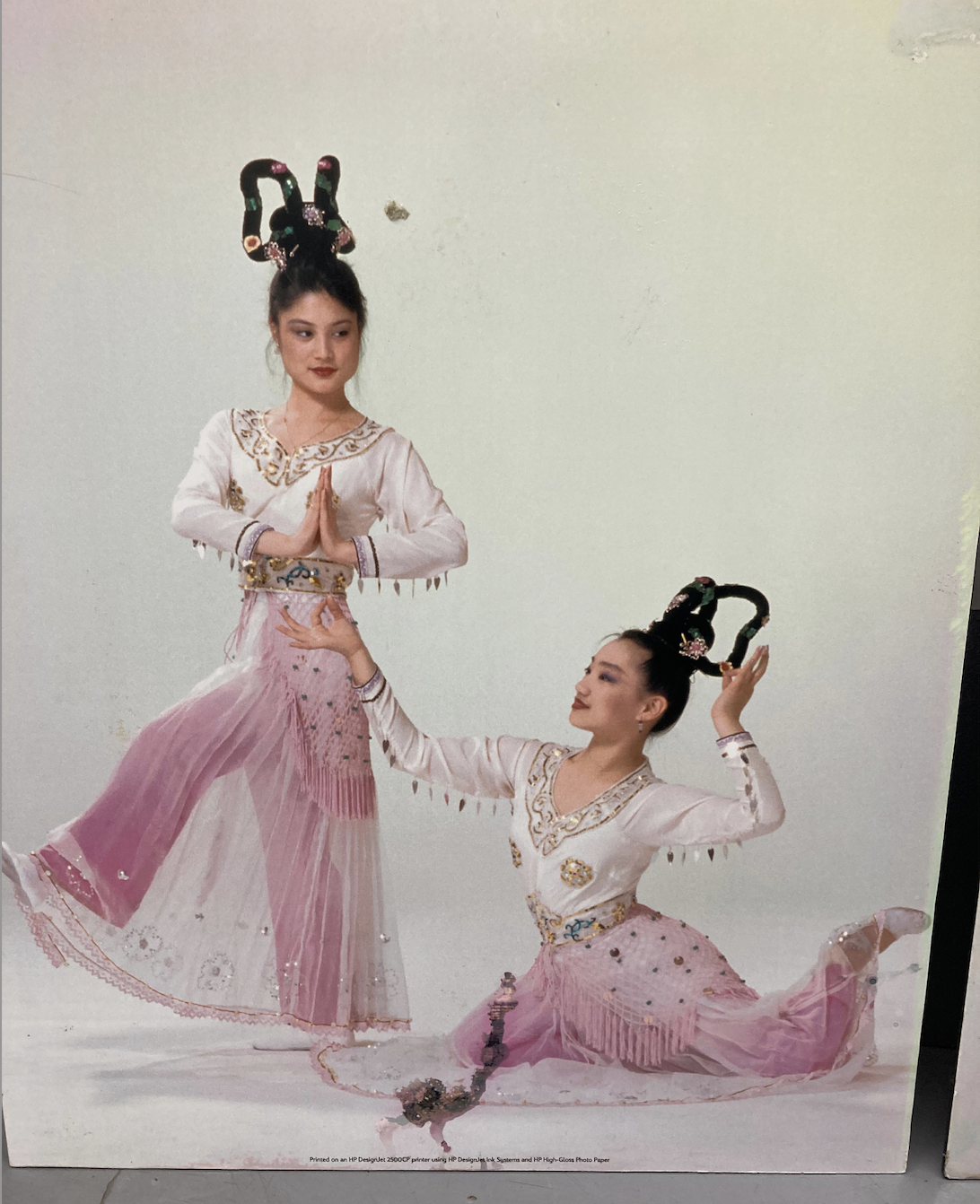 Two female dancers in ornate traditional Chinese costumes and elaborate headdresses performing a graceful pose