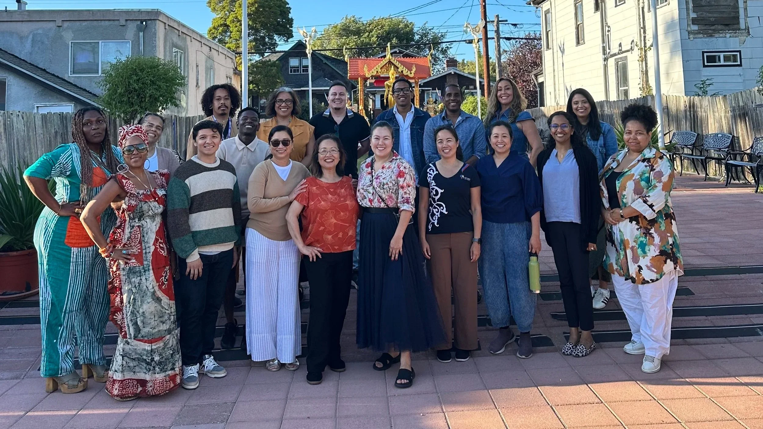 Diverse group posing together outdoors in front of a Thai Buddhist shrine