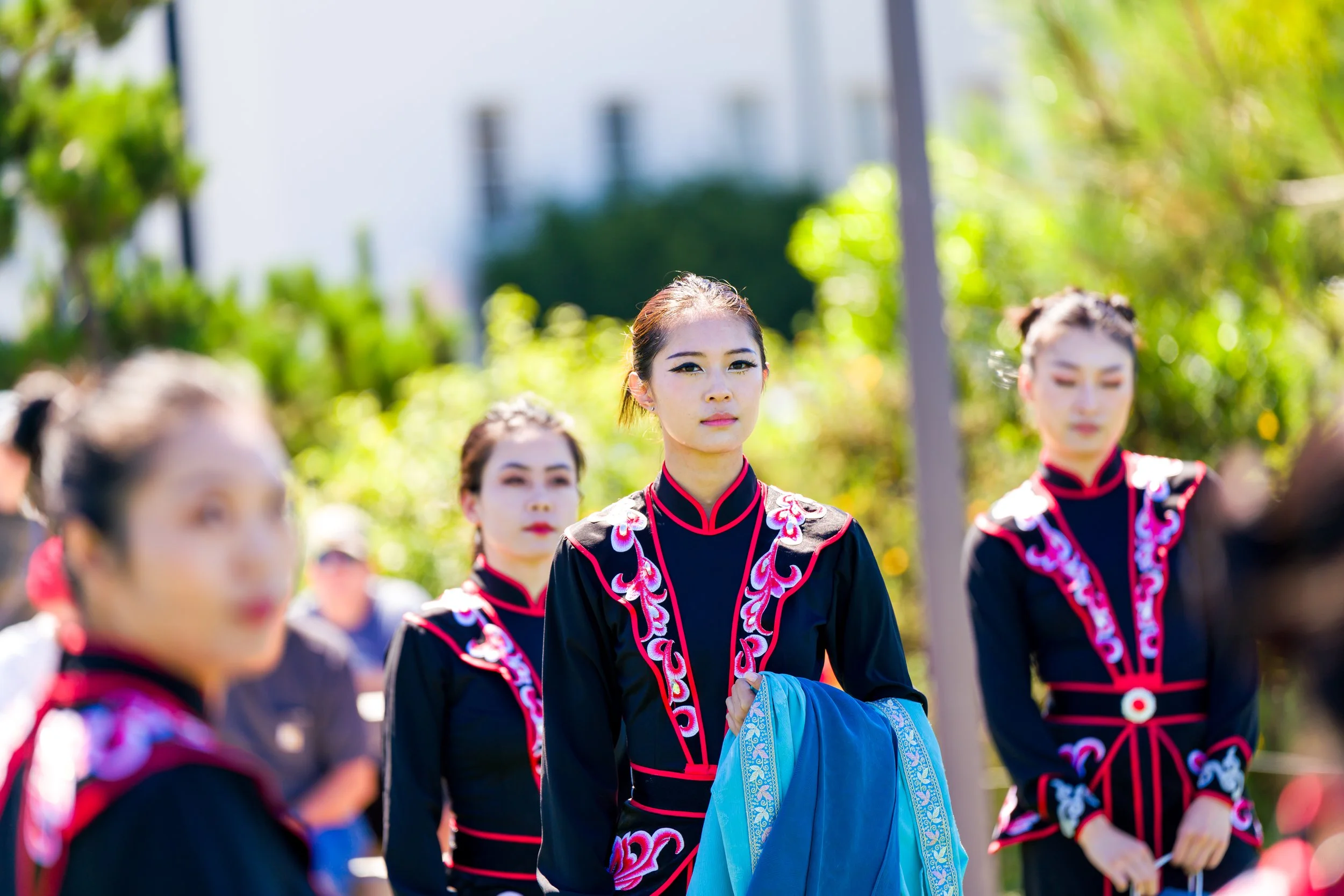 Women in traditional black and red embroidered clothing gathered outdoors