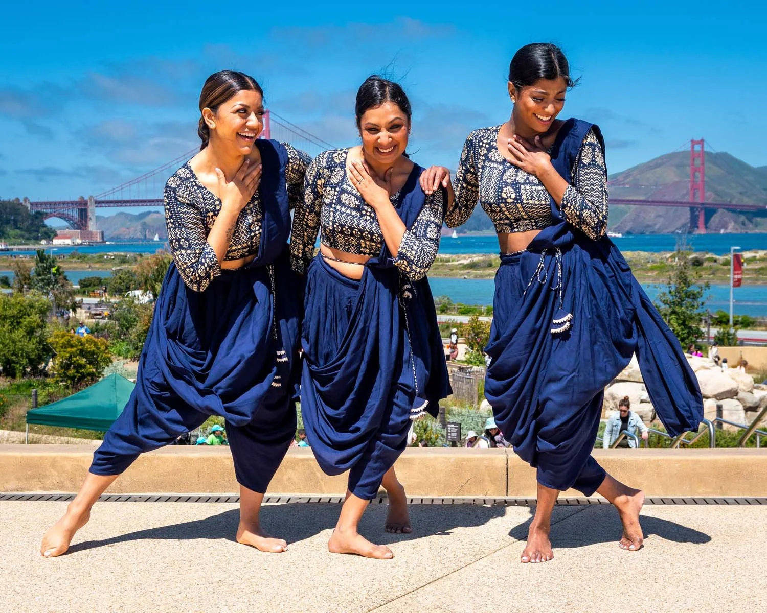 Three women in blue patterned outfits posing in front of San Francisco’s Golden Gate Bridge