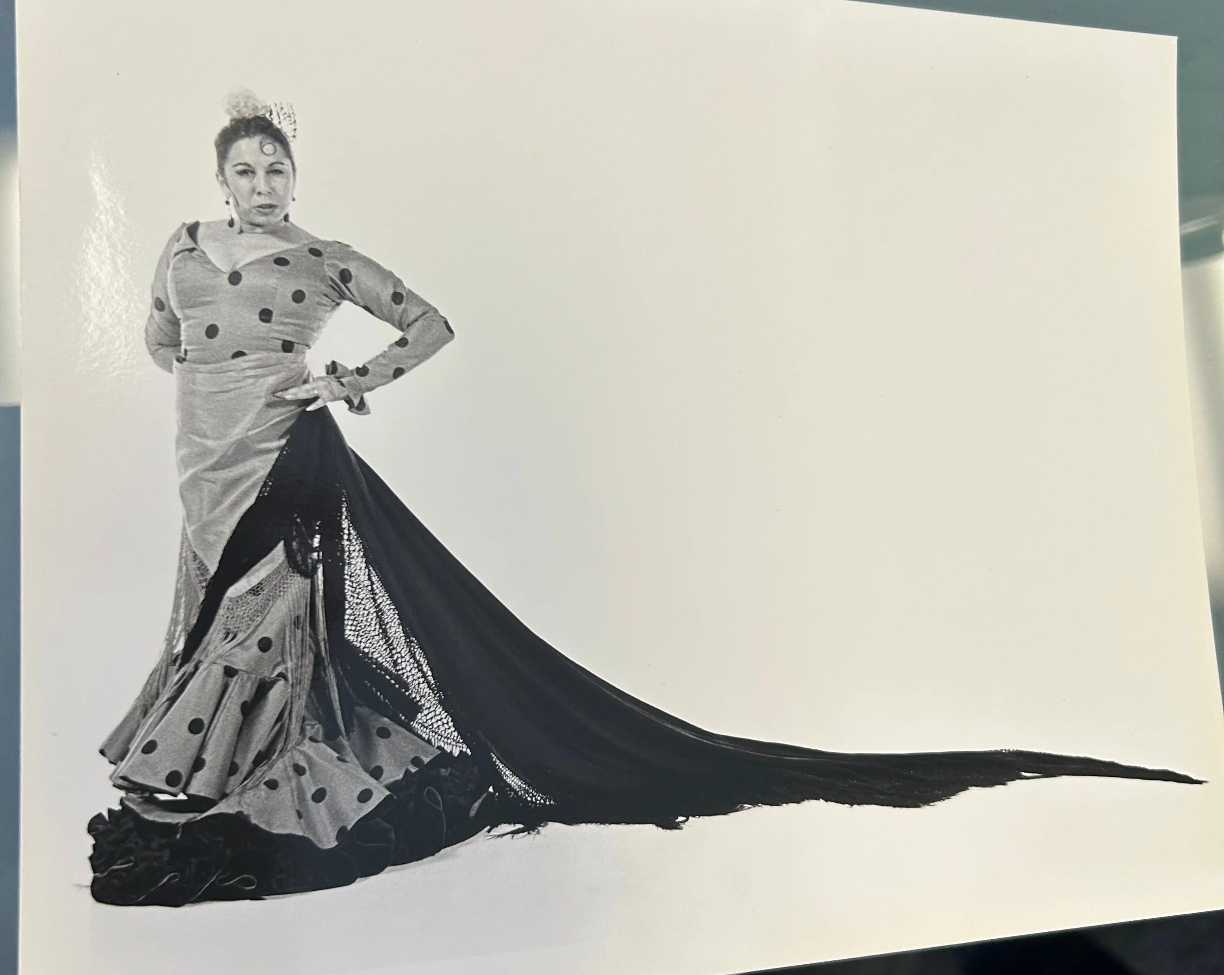 Black-and-white photograph of a woman modeling a polka-dot gown with a dramatic trailing train