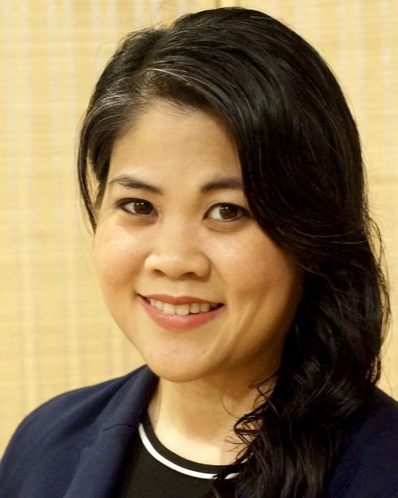 Portrait of a smiling woman with long dark hair wearing a navy blazer